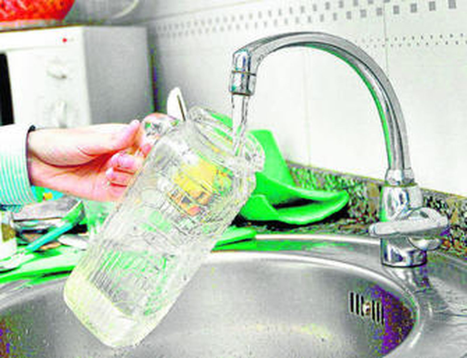 Una mujer llena de agua una jarra.