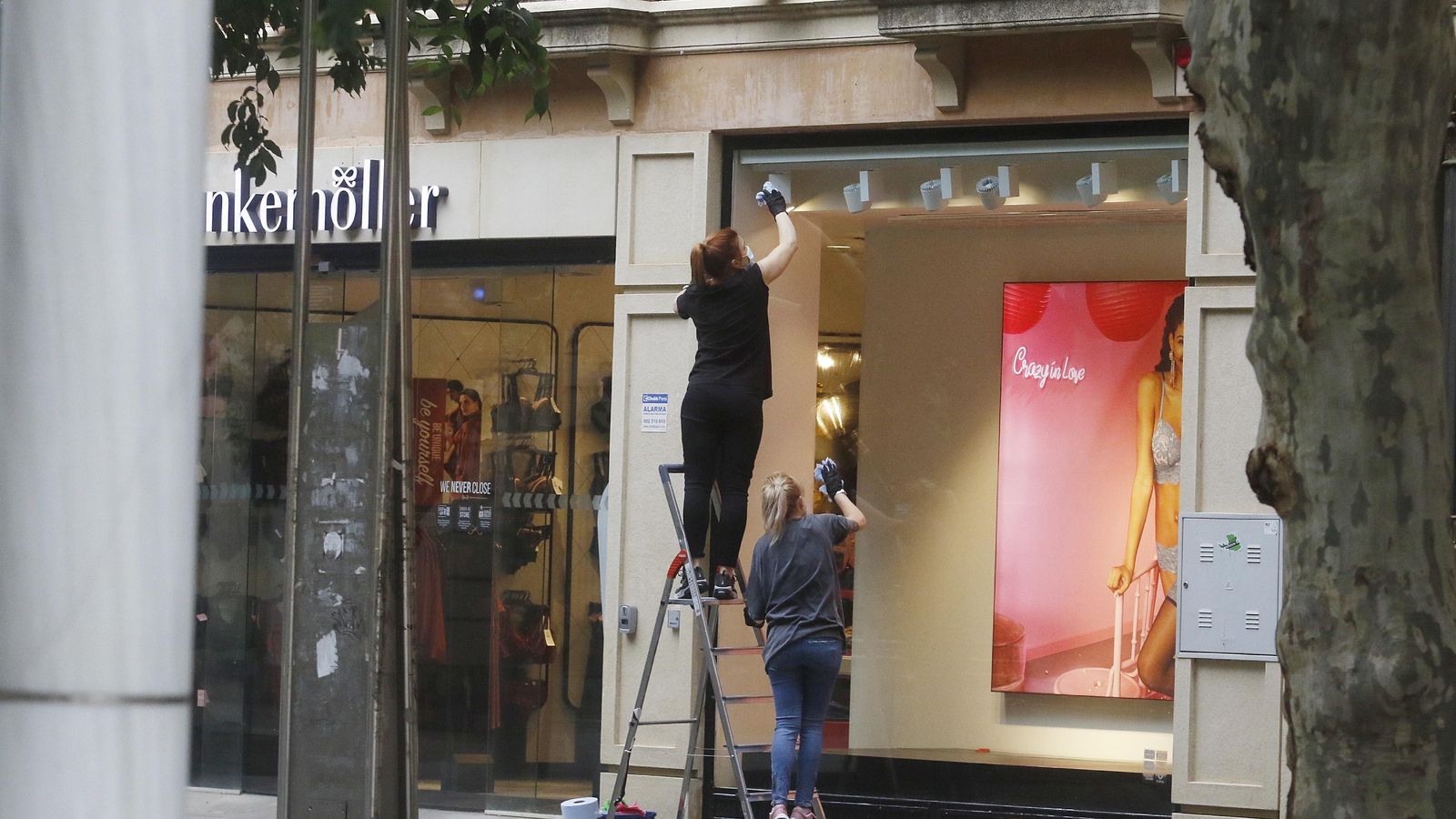 Dos personas limpian el escaparate de una tienda del Centro.