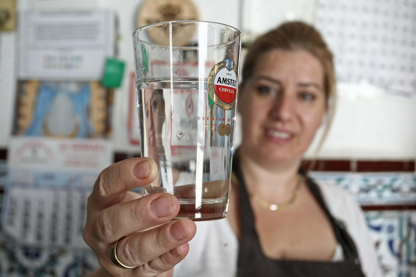Una mujer muestra un vaso de agua.