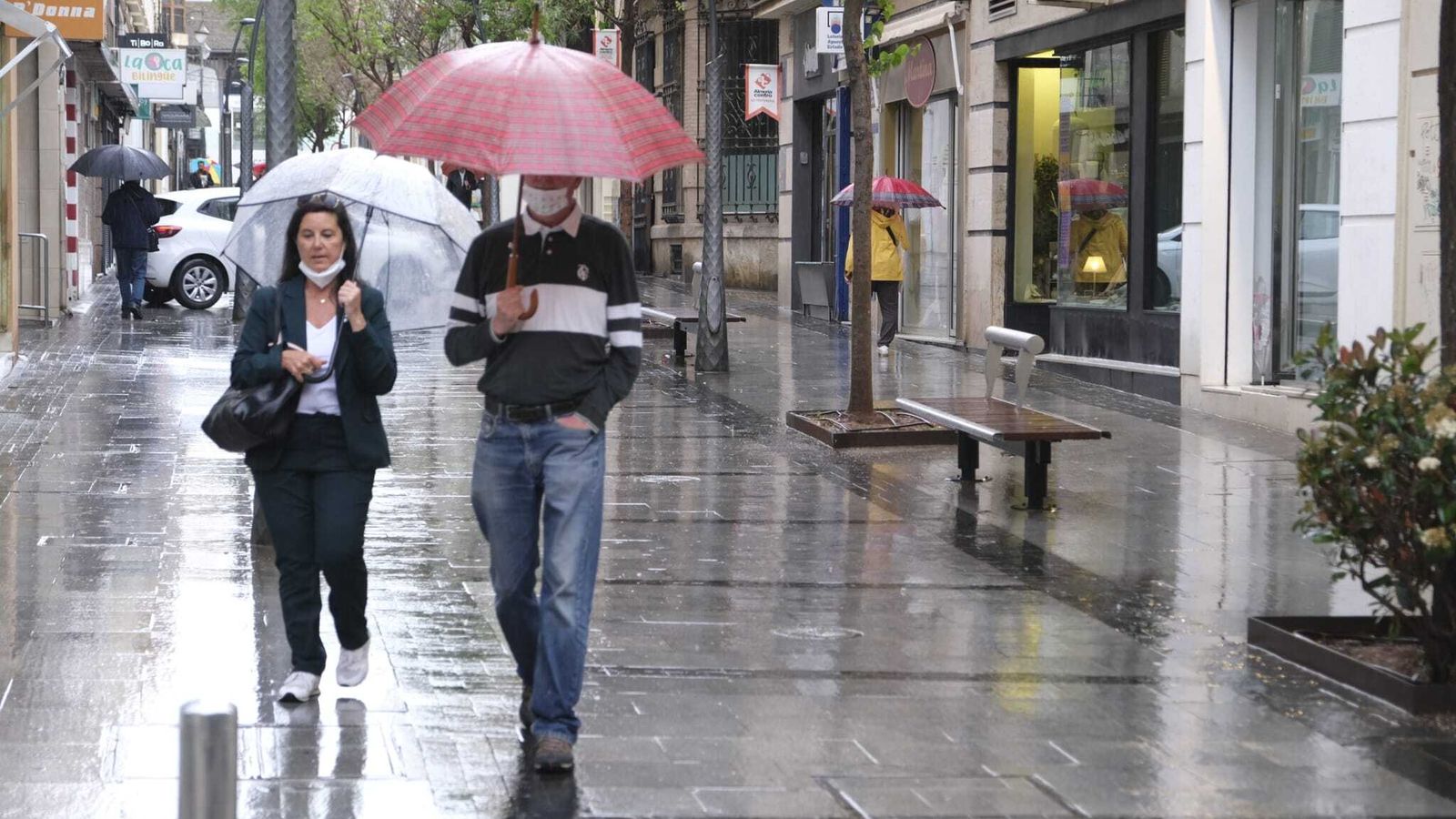 Viandantes en Almería capital con sus paraguas esta mañana.