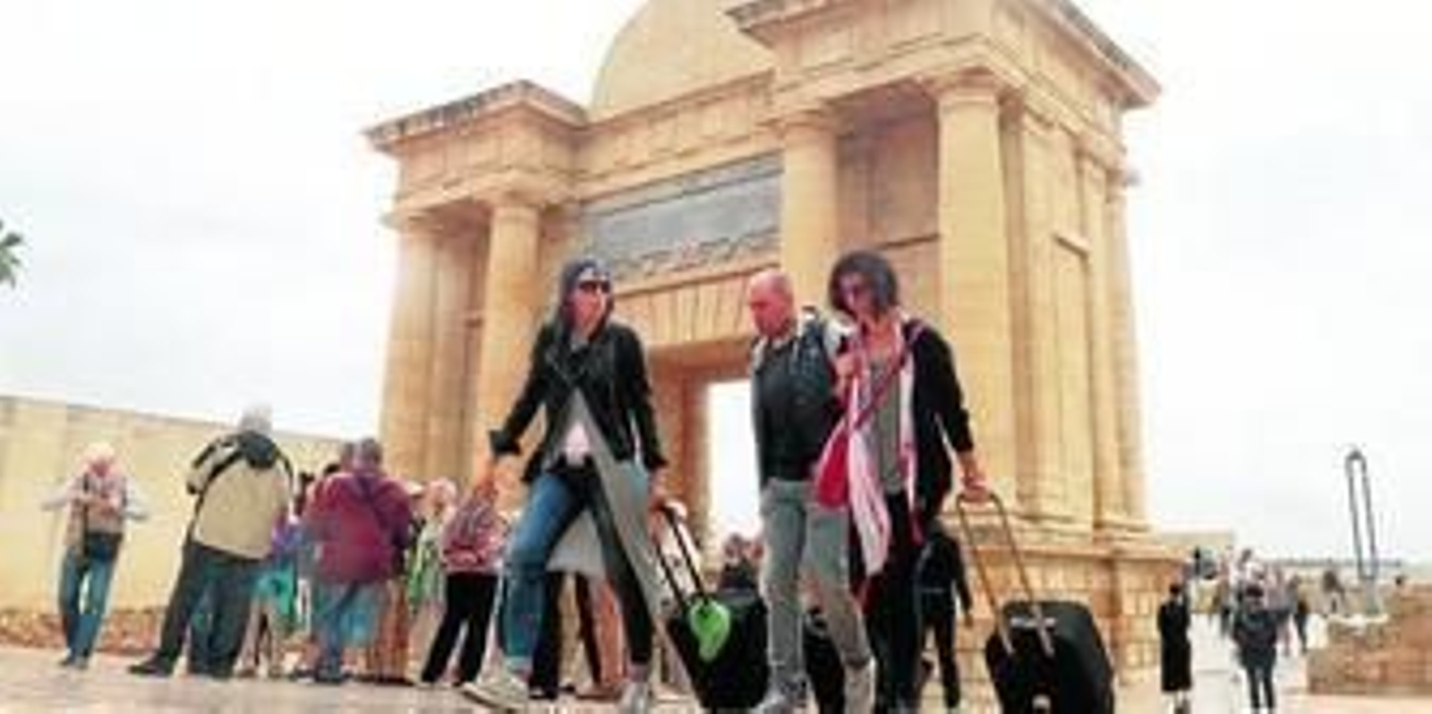 Turistas arrastran sus maletas junto a la Puerta del Puente.