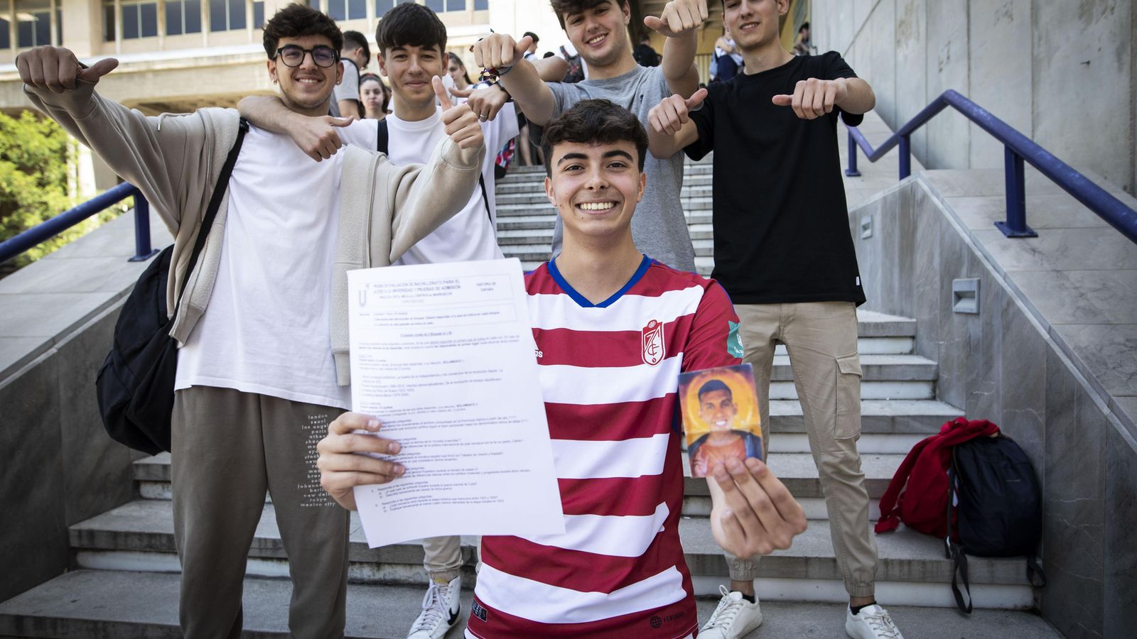 Álvaro muestra su examen de Historia y la estampa de Uzuni rodeado de sus compañeros.