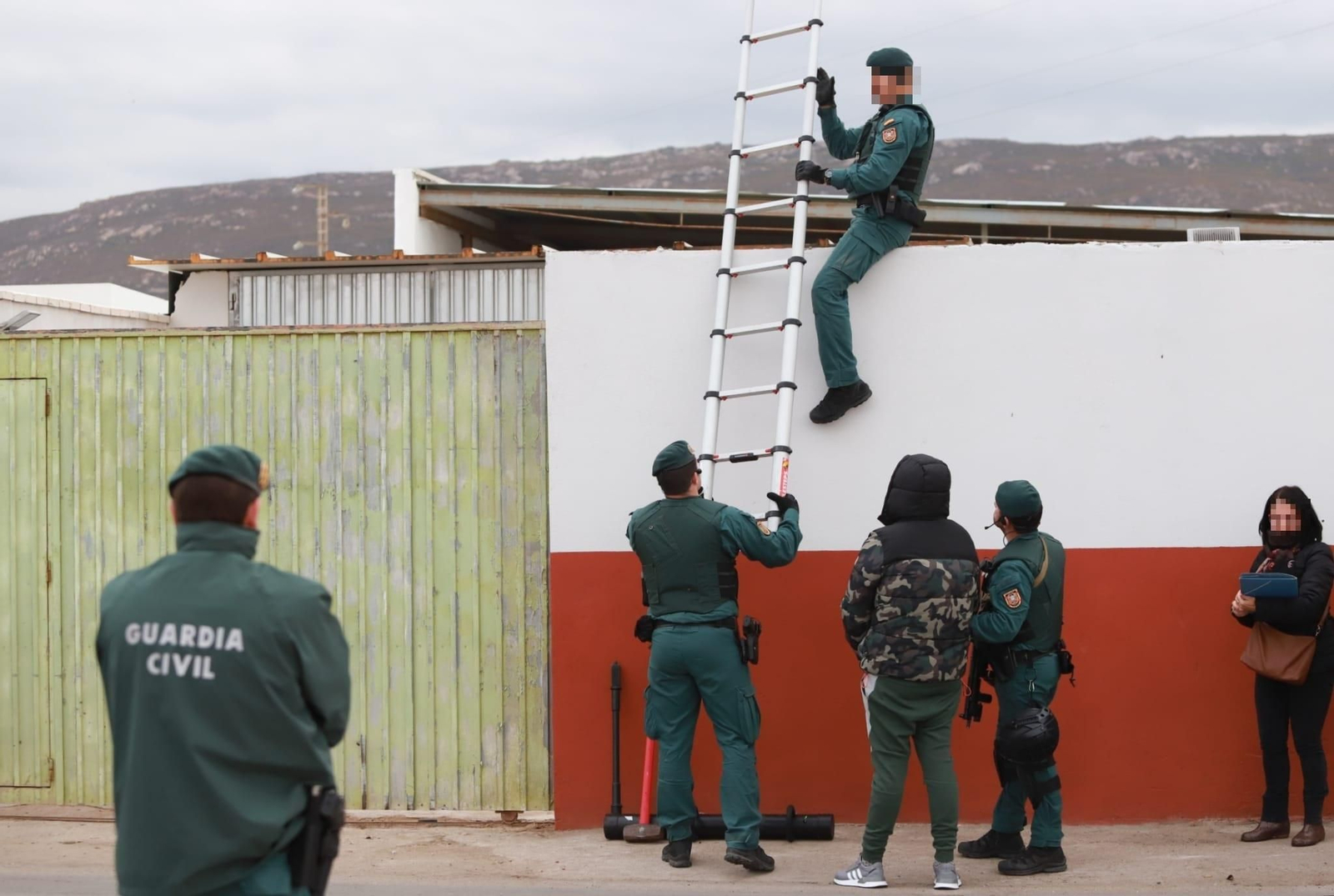 Un agente entra en la finca situada en el Camino de Sobrevela, en presencia de un detenido.