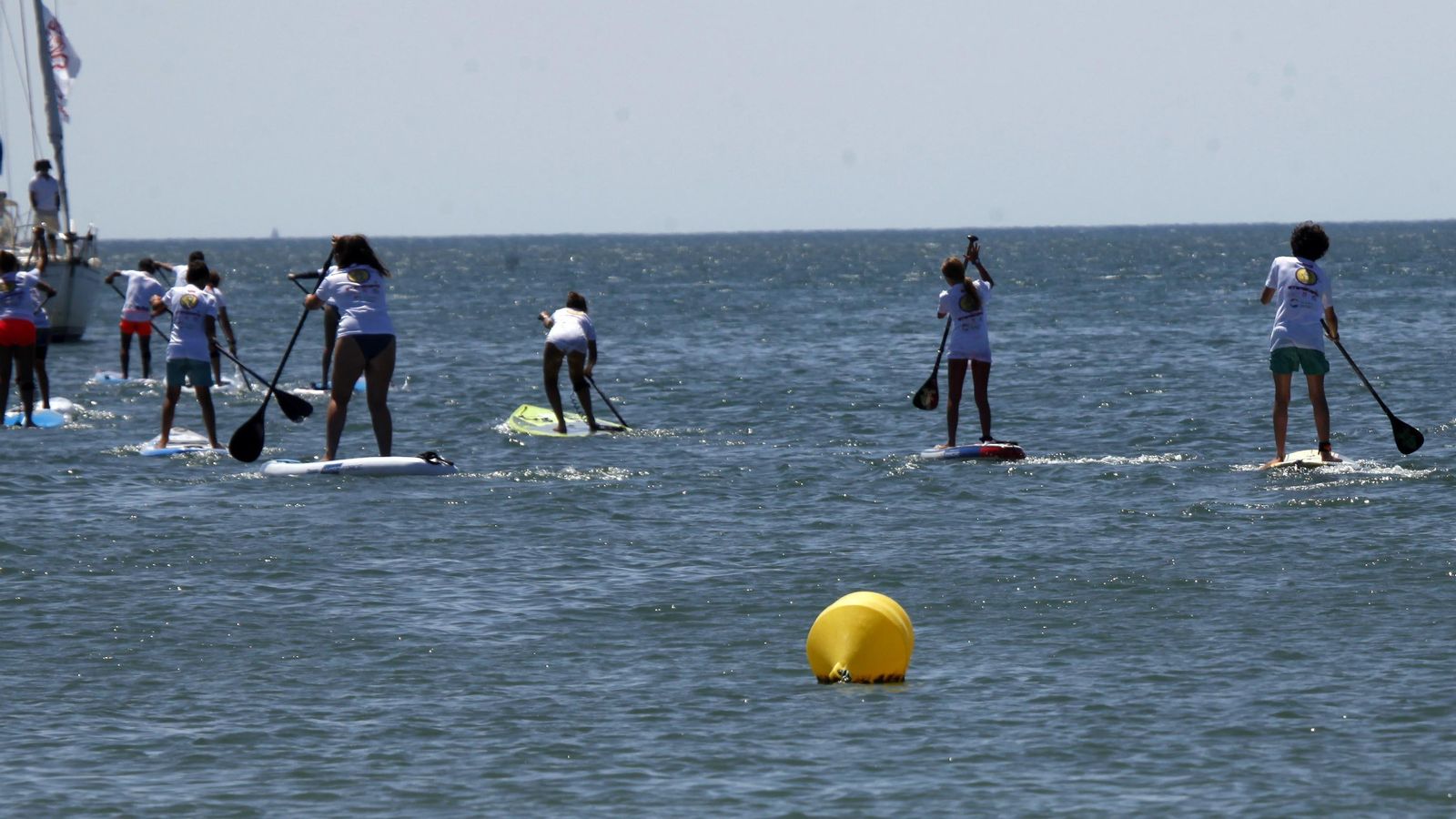 Varios palistas participan en una competición de pádel surf en una playa de Huelva