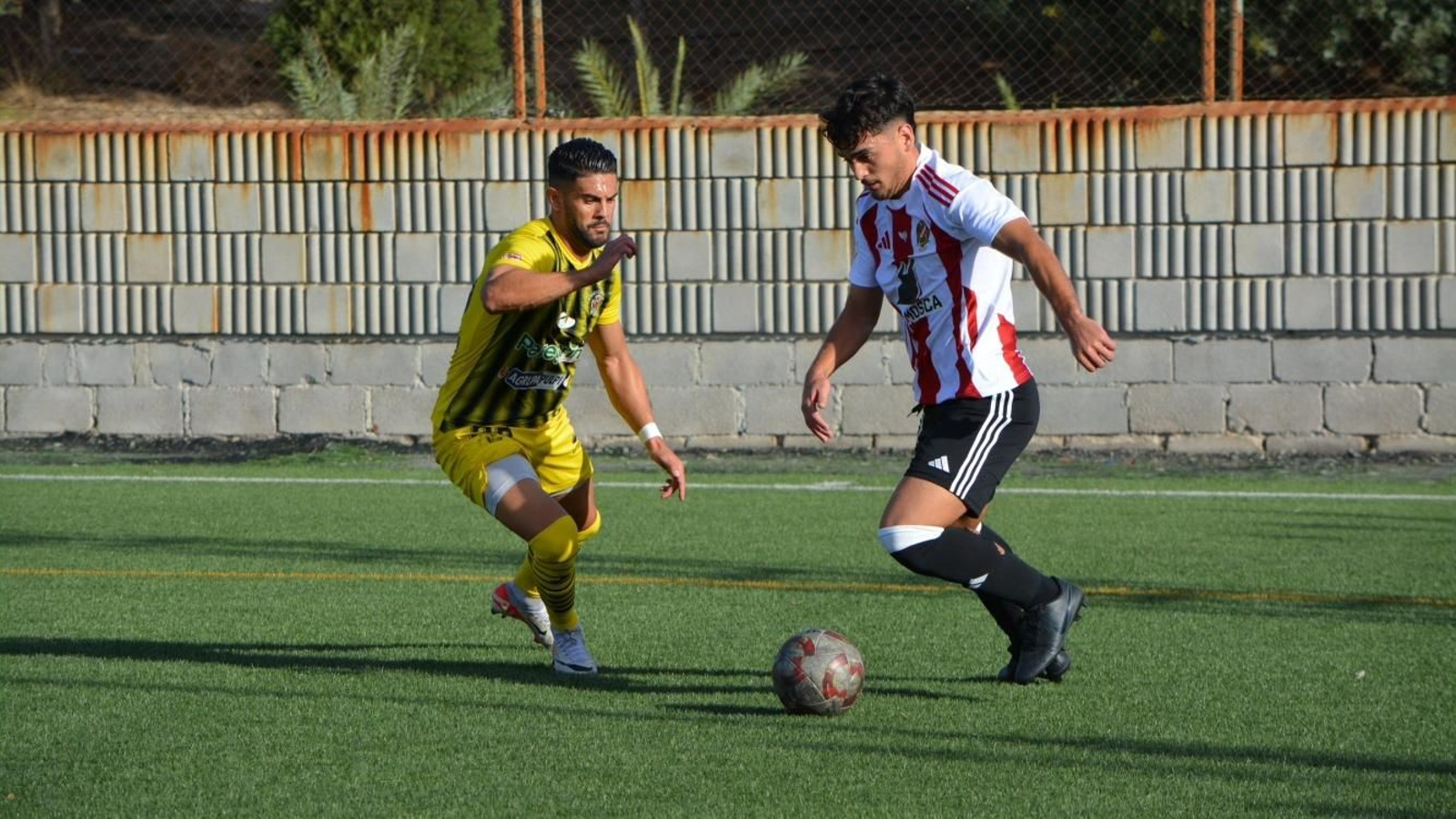 Fran Perujo busca cortar la progresión del futbolista pimentonero.