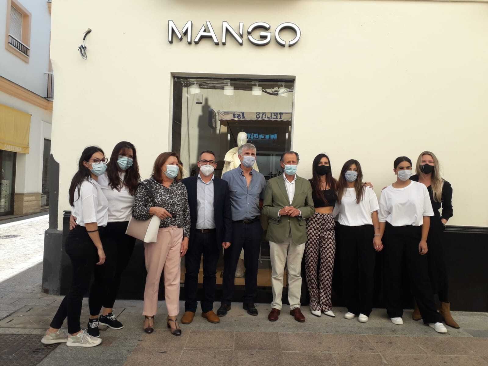 Los representantes municipales y los responsables del proyecto posan a las puertas de la nueva tienda.