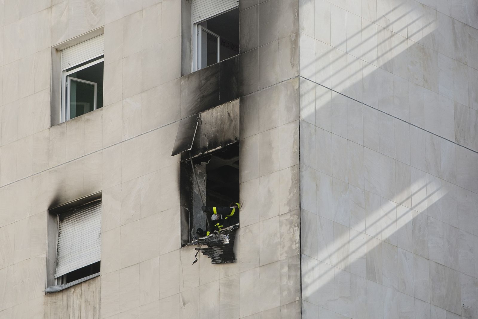 Los bomberos retirando algunas partes dañadas del exterior del edificio.