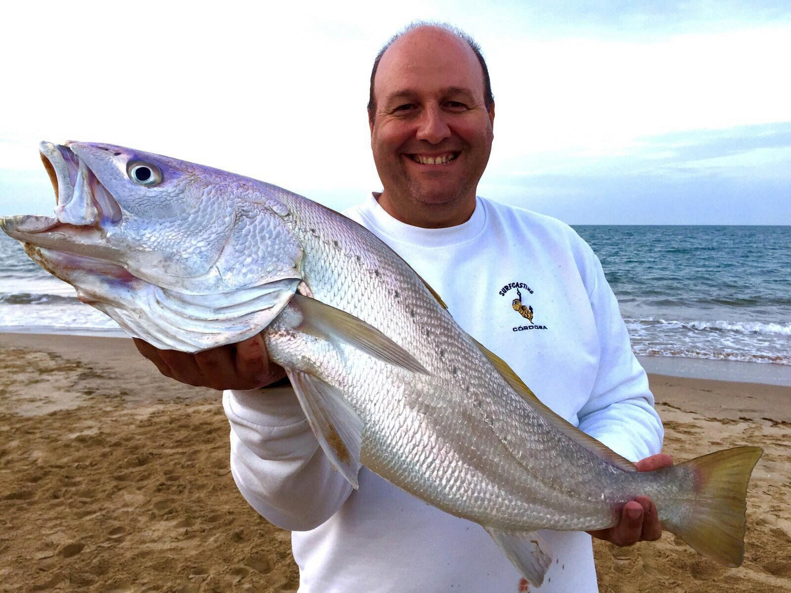 Antonio Eslava muestra una corvina de 7 kilos capturada en las costas onubenses