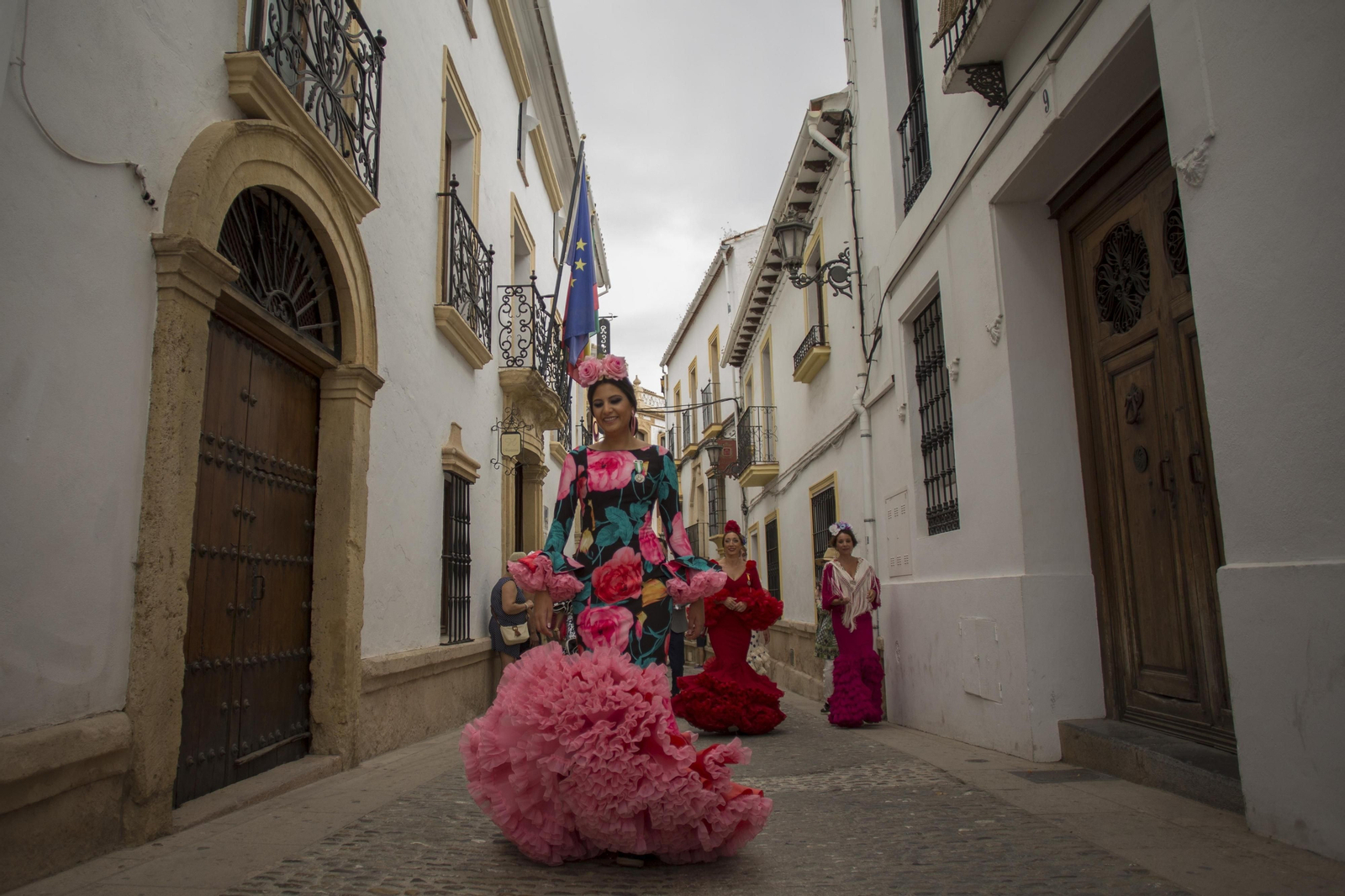 Mujeres ataviadas de flamenca pasean por el casco antiguo de Ronda.