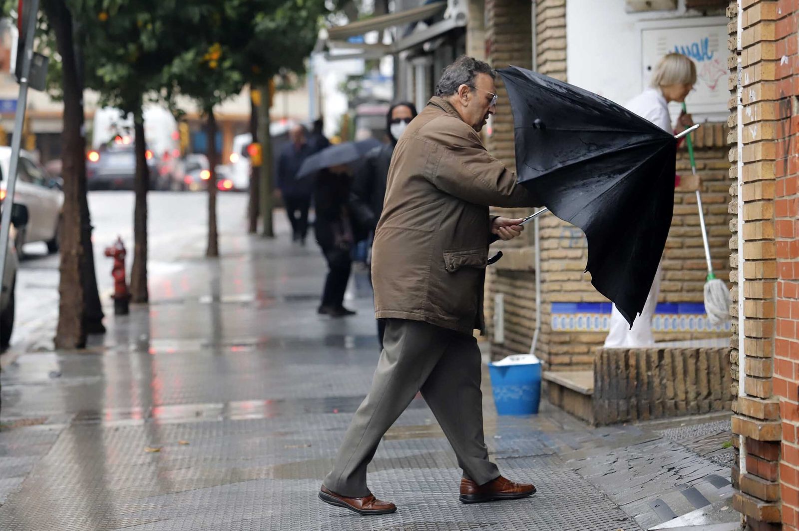 Un hombre recoge su paraguas para entrar en un portal.