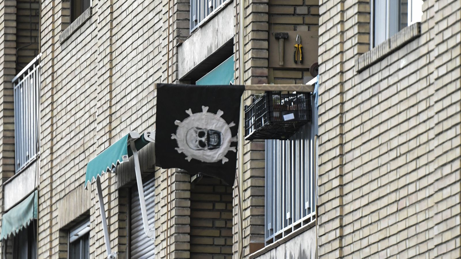 Una pancarta con el coronavirus y una calavera dentro ondea en un balcón.