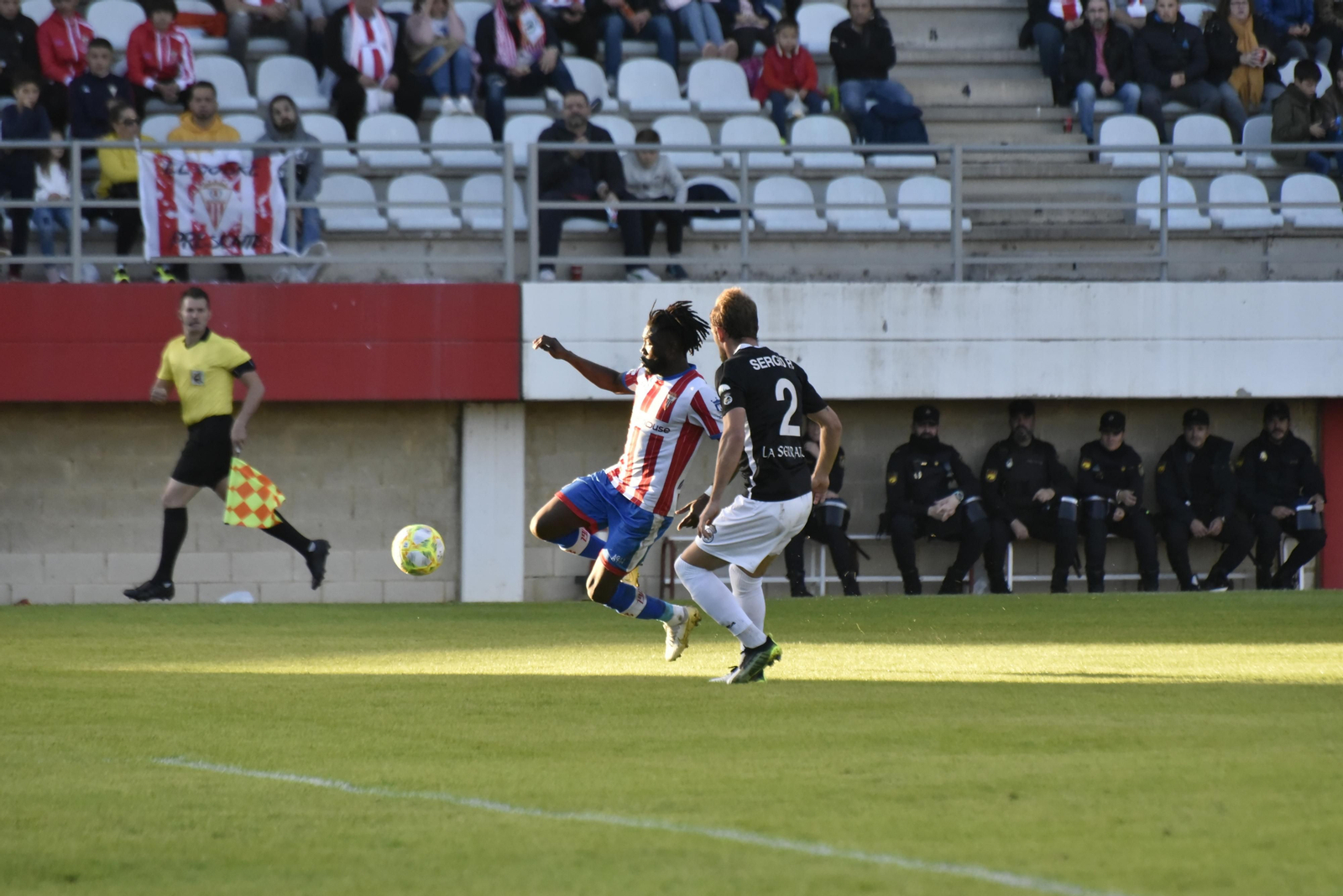 Karim se dispone a centrar en postura acrobática, defendido por Sergio Rodríguez