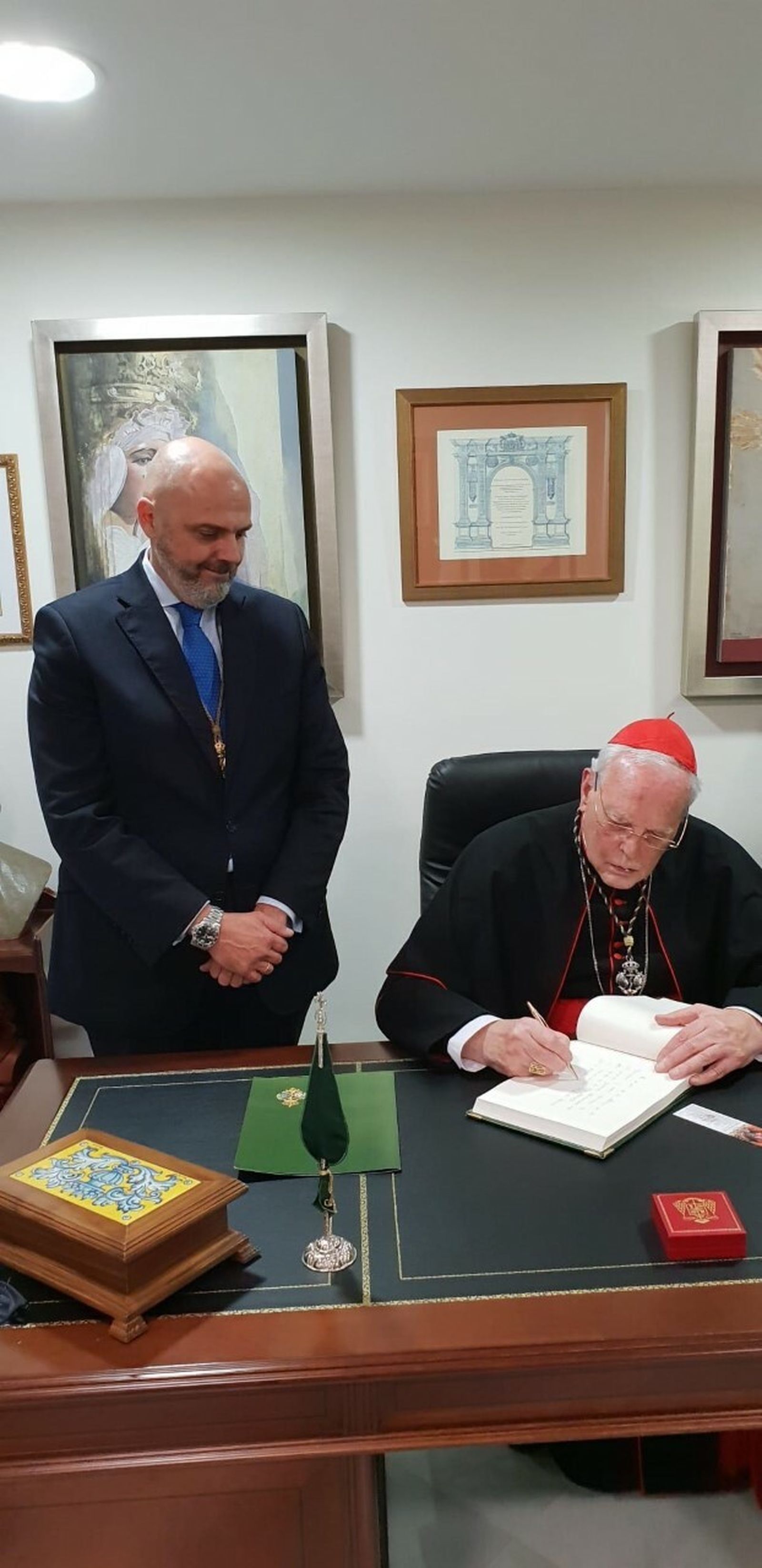 El cardenal Amigo firmando en el libro de honor de la hermandad.