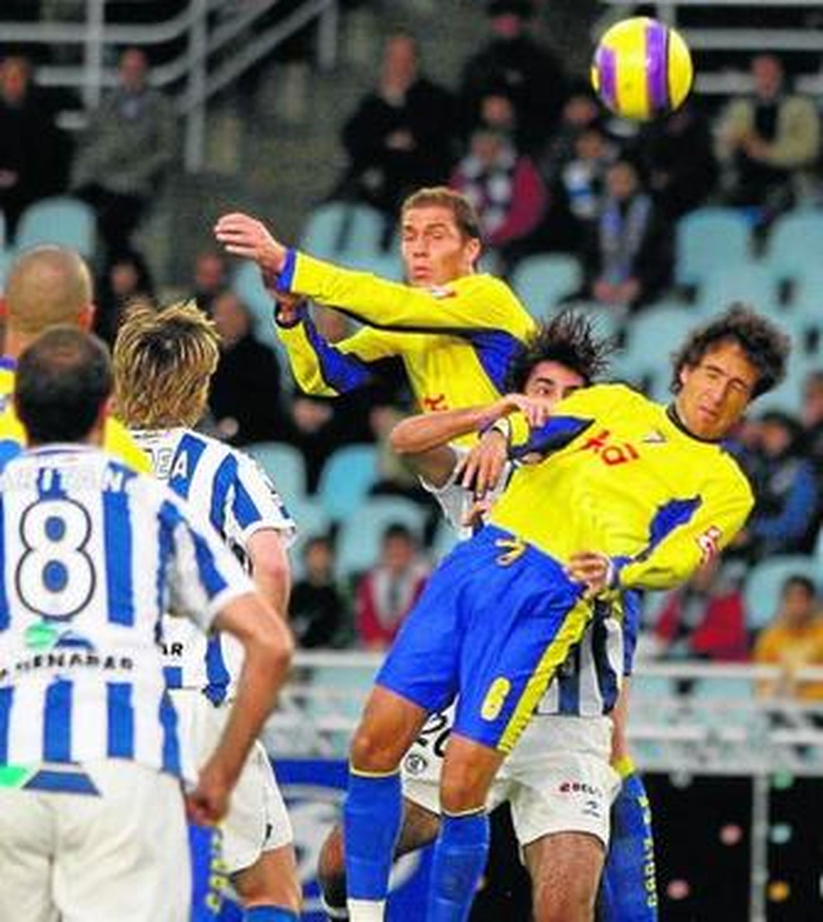 Nano y César Caneda saltan junto a un jugador donostiarra en el último Real Sociedad-Cádiz.