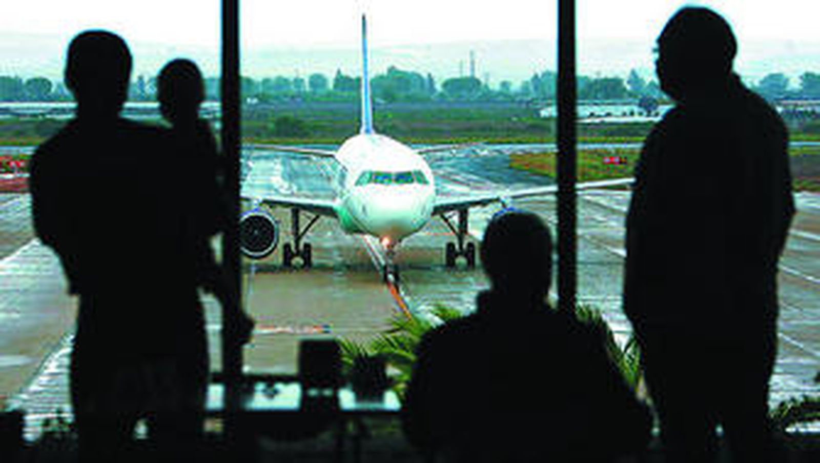 Varios usuarios del aeropuerto de Jerez observan desde la cafetería de la terminal las maniobras de un avión de Ryanair.