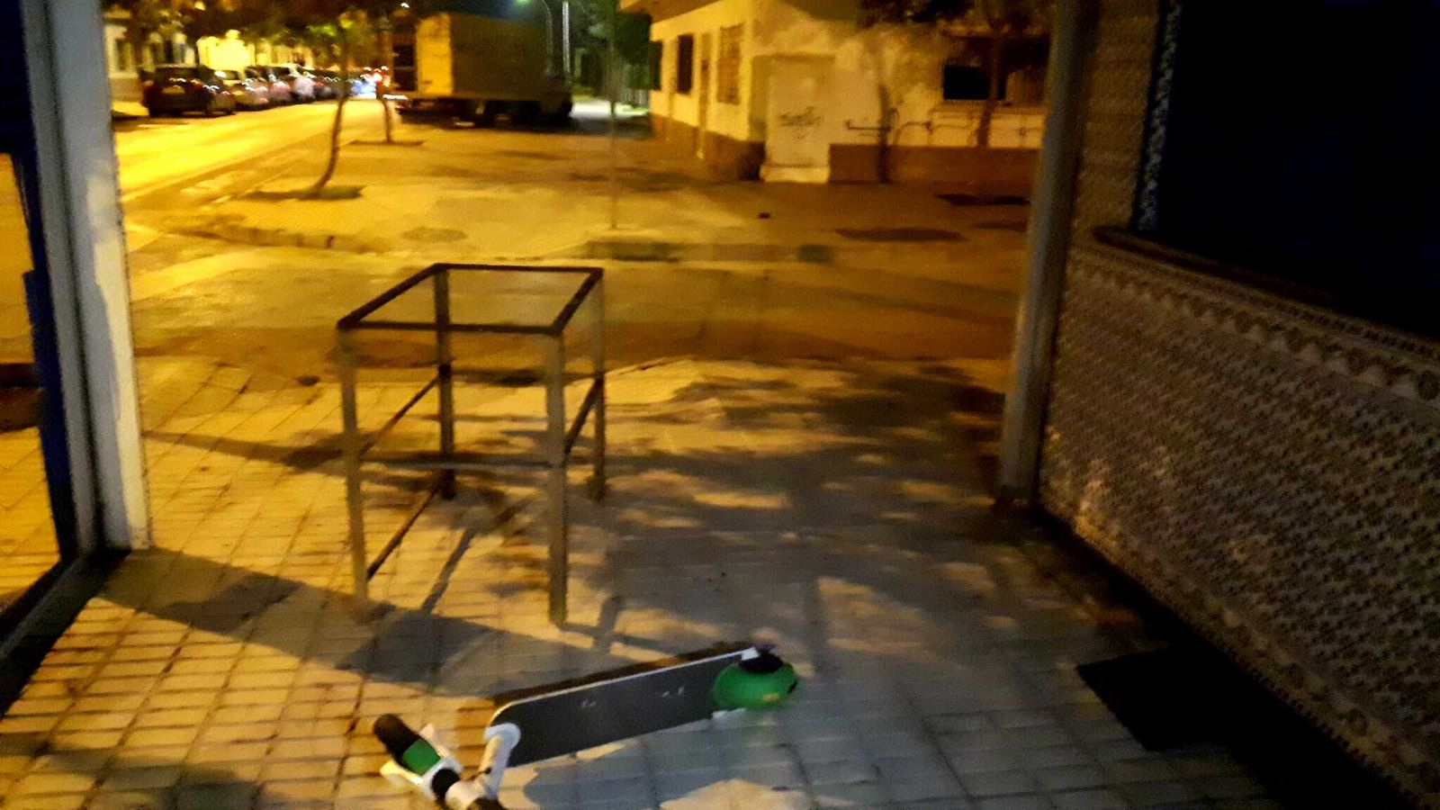un patinete y una mesa, junto al quiosco de noche.
