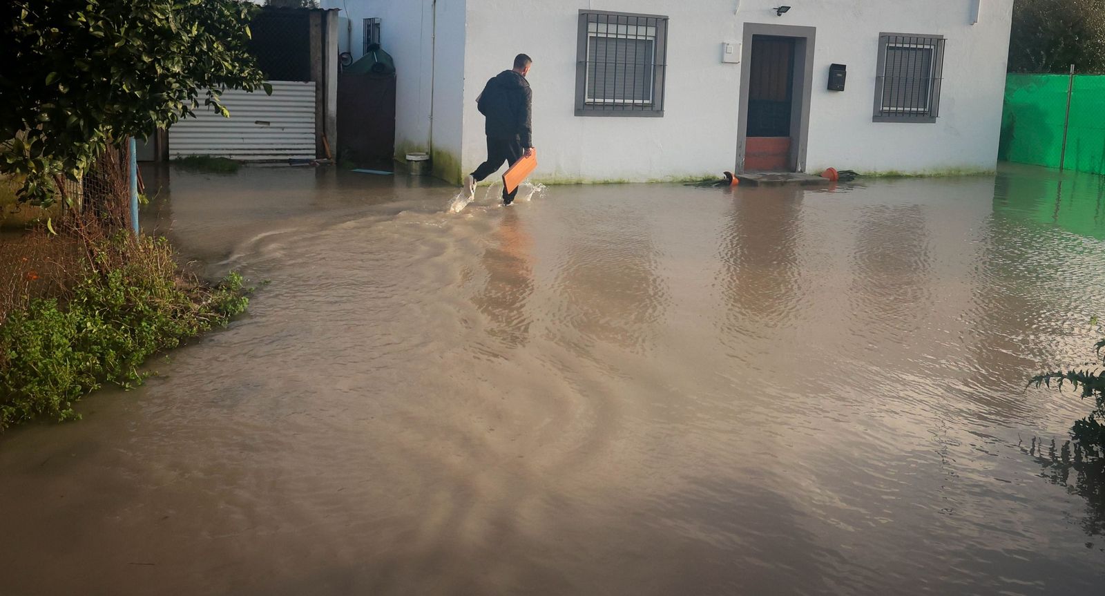 Un vecino accediendo a su vivienda anegada por el agua.
