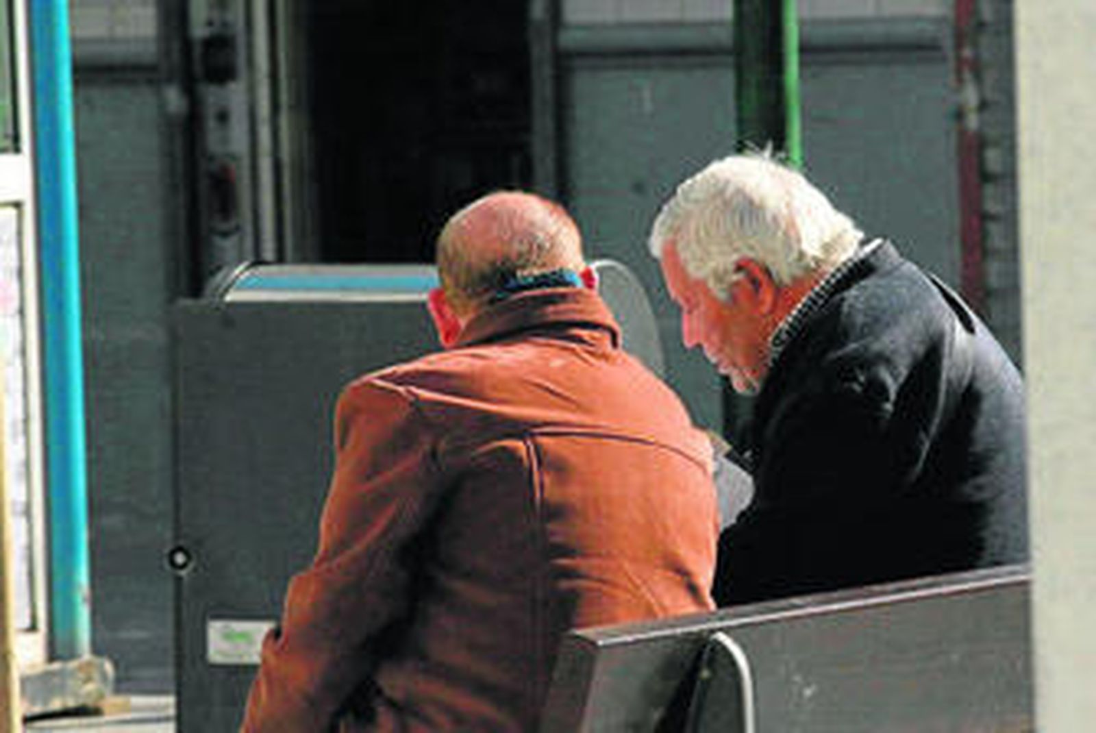 En la imagen se ve a dos ancianos sentados en un banco.