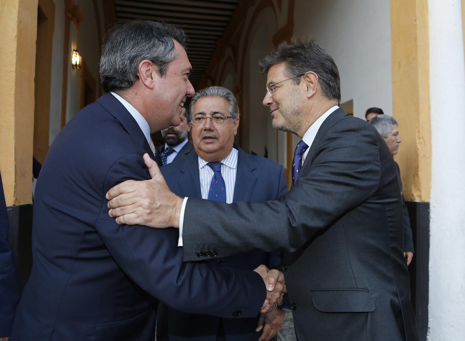 El alcalde de Sevilla, Juan Espadas, y Rafael Catalá se saludan en presencia de Juan Ignacio Zoido, ministro del Interior.