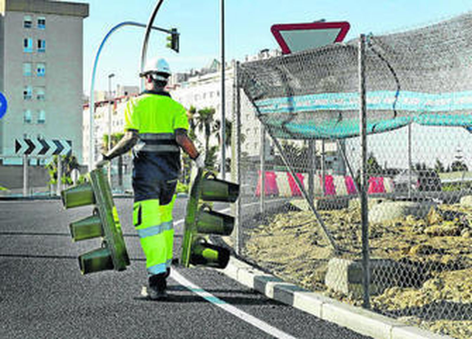 Un operario lleva dos semáforos para colocarlos en la rotonda de El Corte Inglés de la orilla gaditana.