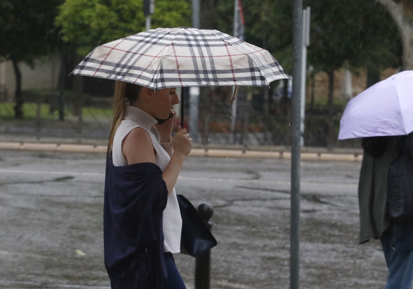 Una mujer se protege de la lluvia con un paraguas.
