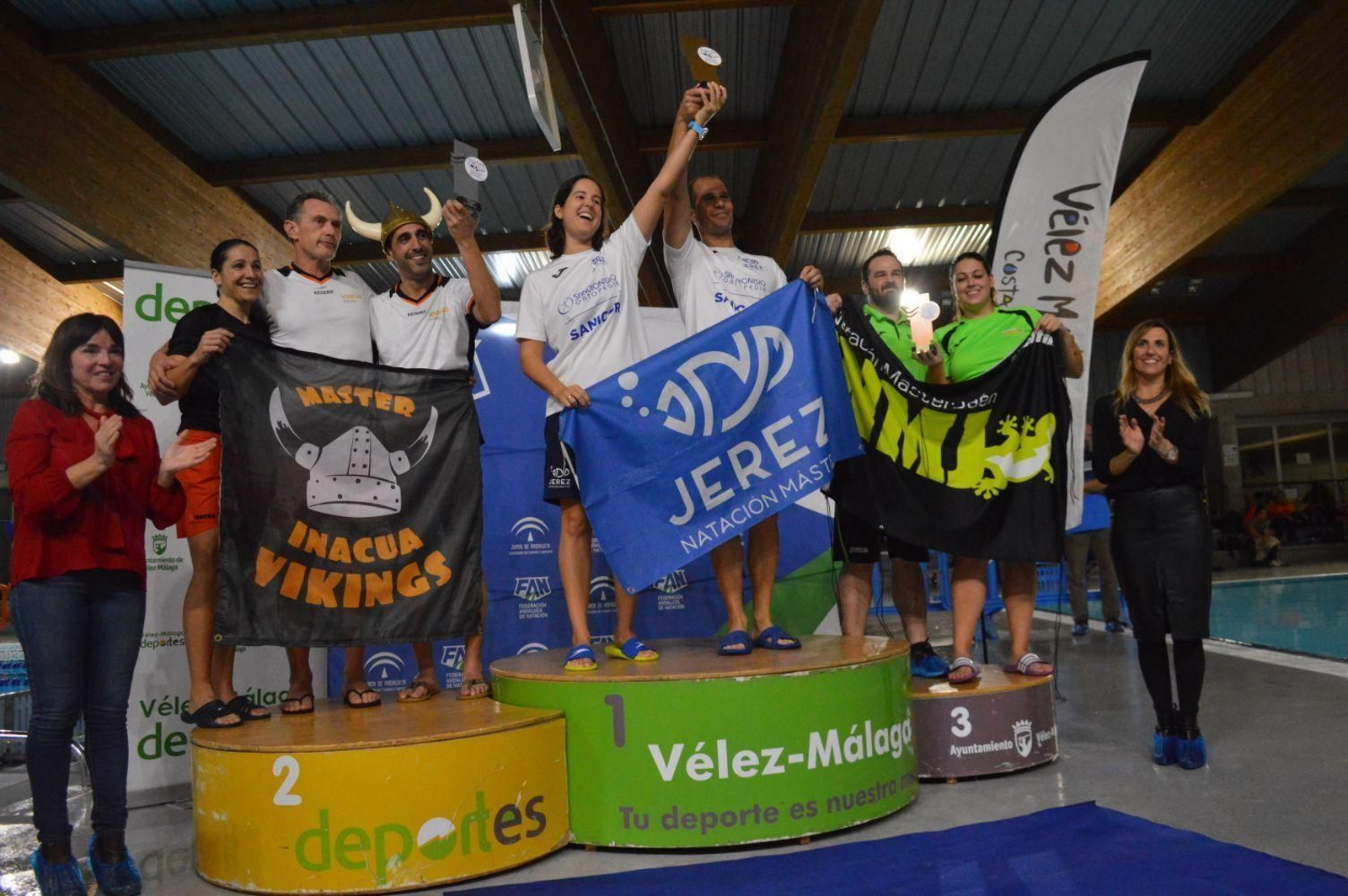 Zabeli Sánchez y Álvaro Bernal, capitanes  del Jerez Natación Máster, levantando el trofeo de campeones de Andalucía en lo alto del podio de Torre del Mar.