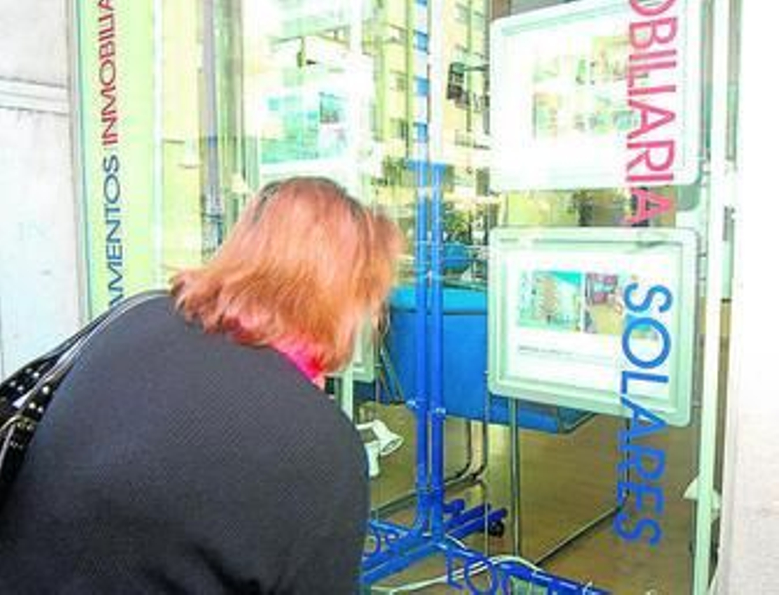 Una mujer observa un anuncio en el escaparate de una inmobiliaria.