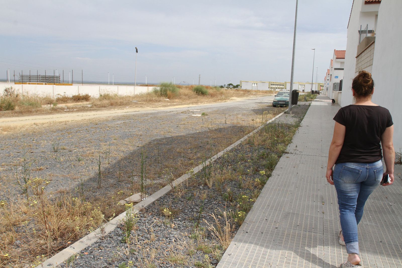 Una vecina camina por la calle posterior de la urbanización que está sin urbanizar.