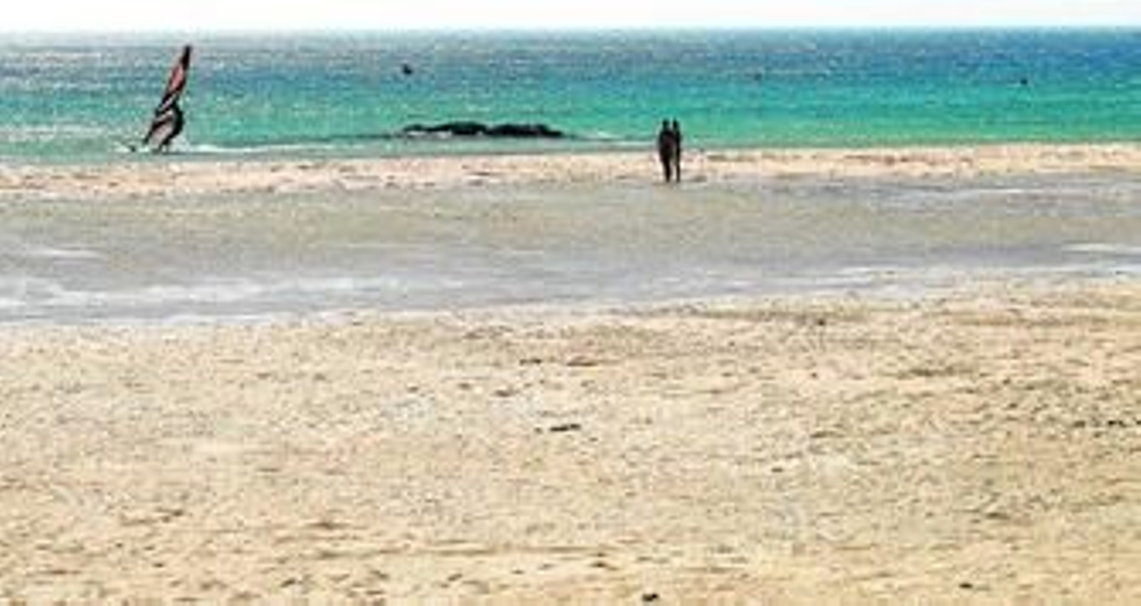 Una pareja observa a un windsurfista, ayer en Los Lances.