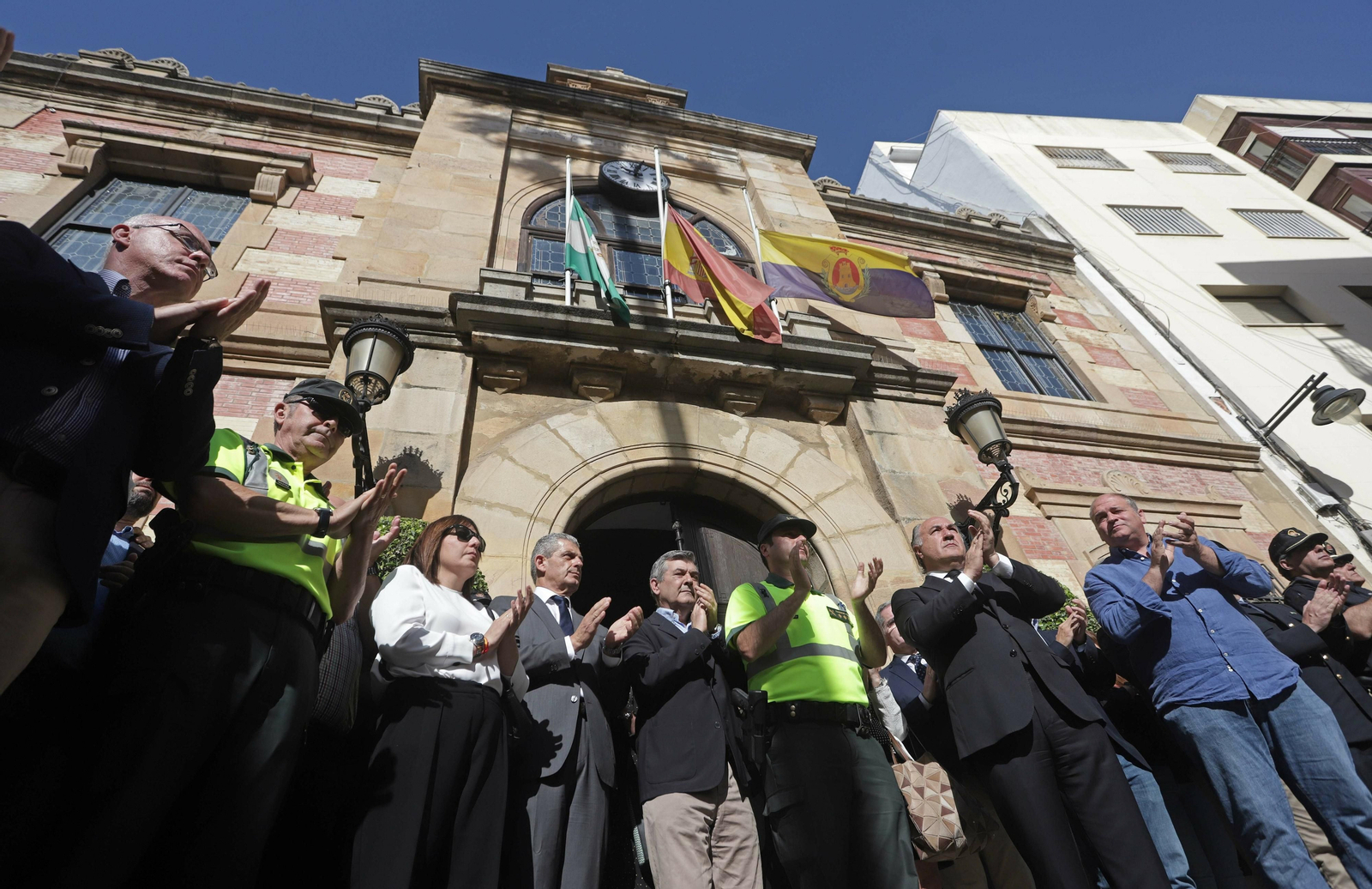 Las autoridades y agentes de la Guardia Civil aplauden tras la concentración bajo las banderas a media asta en el Ayuntamiento de Algeciras.