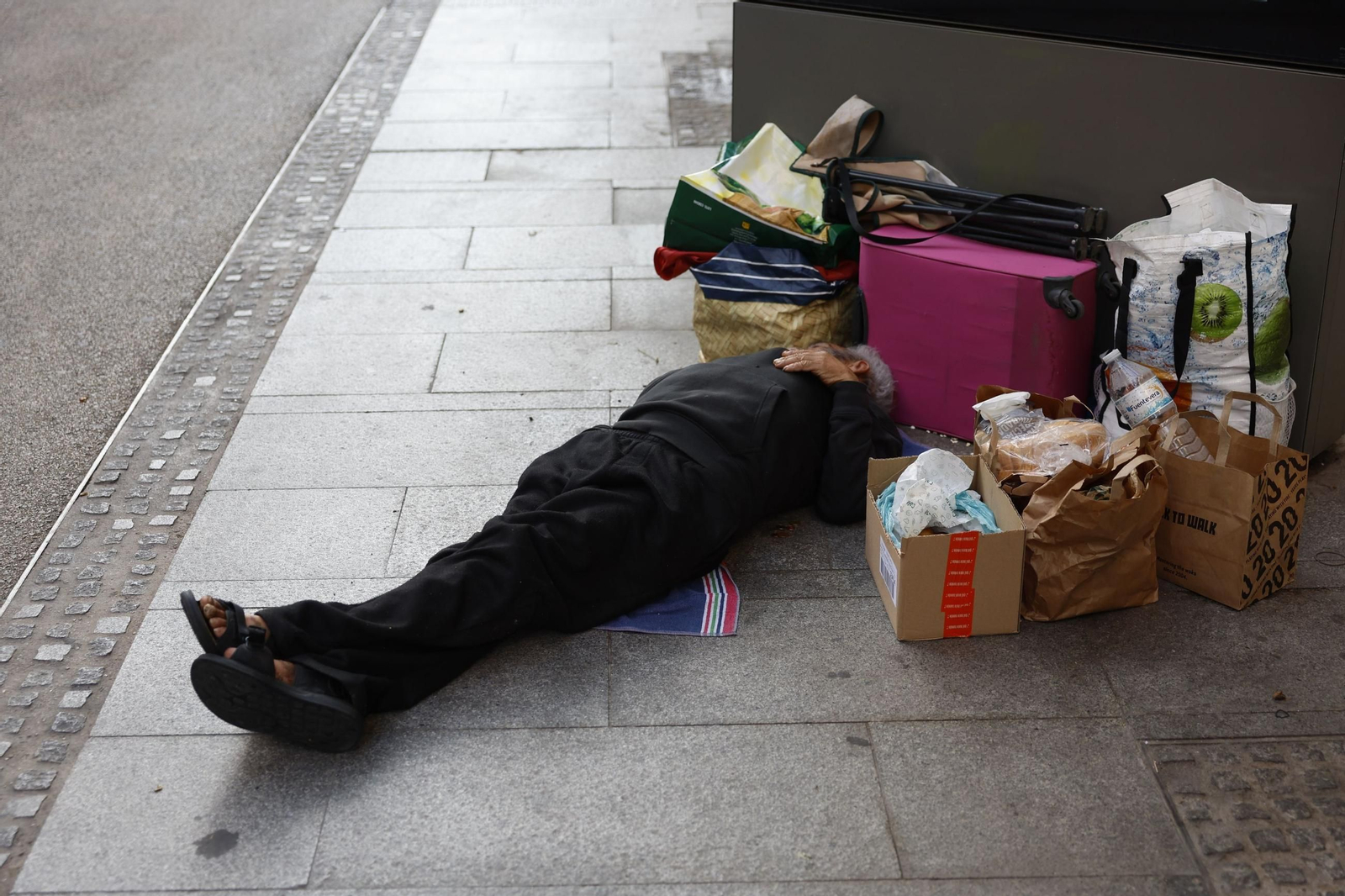 Una persona duerme en la calle rodeada de sus escasas pertenencias en Madrid.