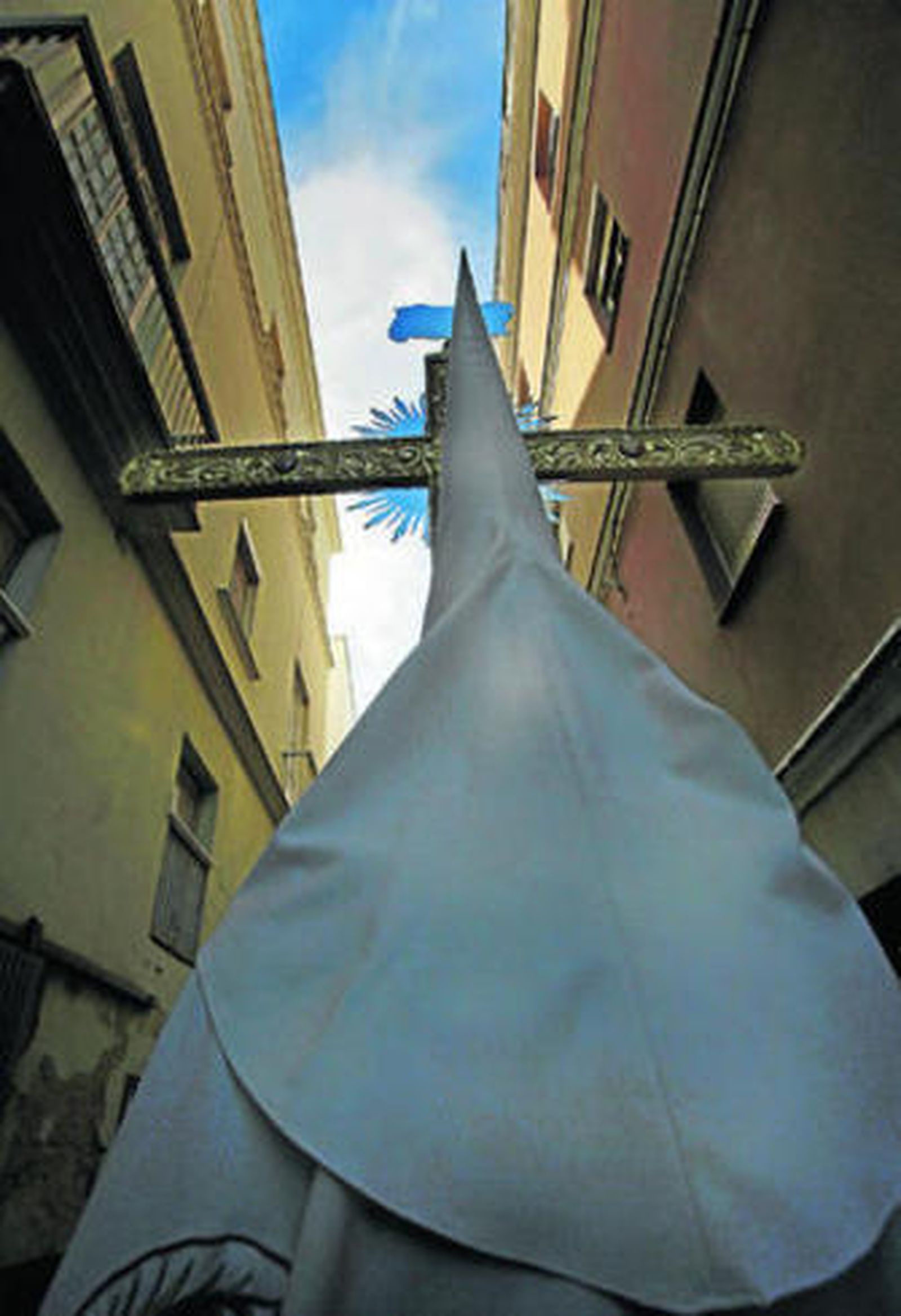 El sol se asoma entre los edificios ante un penitente.