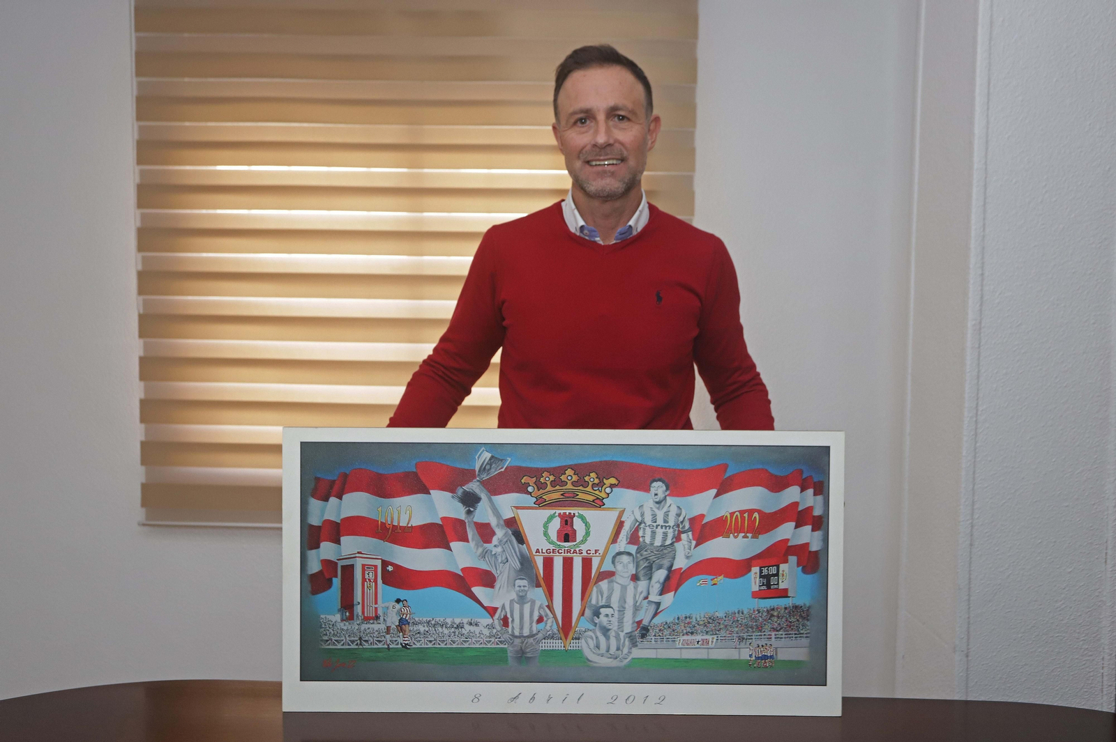 Miguel Ángel García, con el cuadro del centenario, en su despacho.