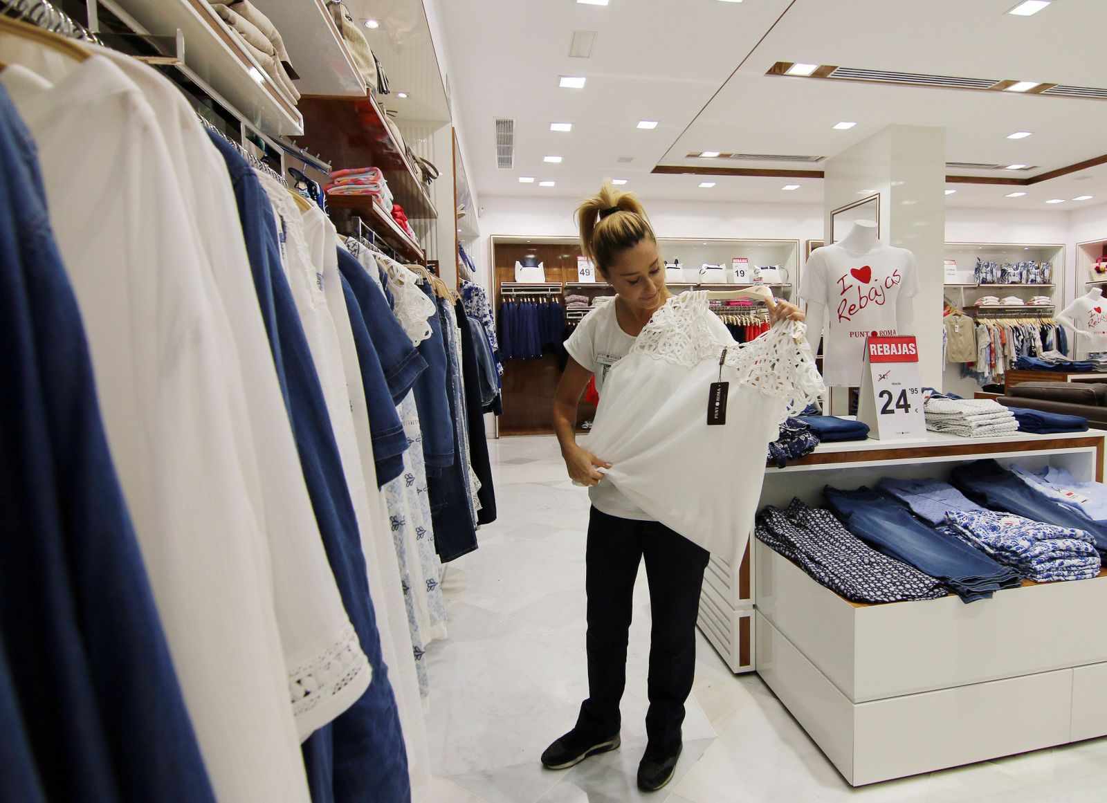 Una dependienta muestra una camiseta en una tienda.