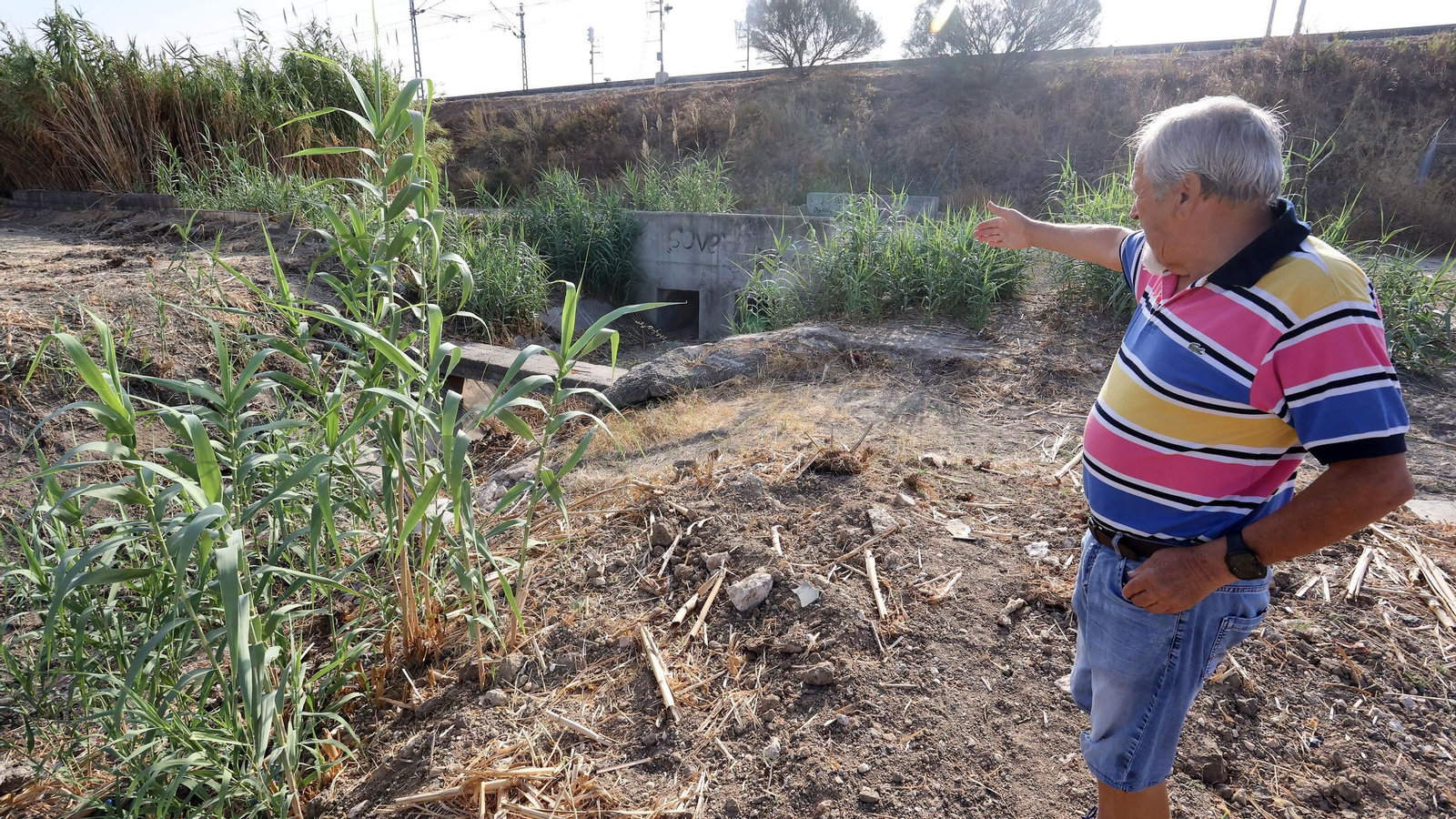Un vecino muestra el estado del canal a su paso por la barriada de La Flores.