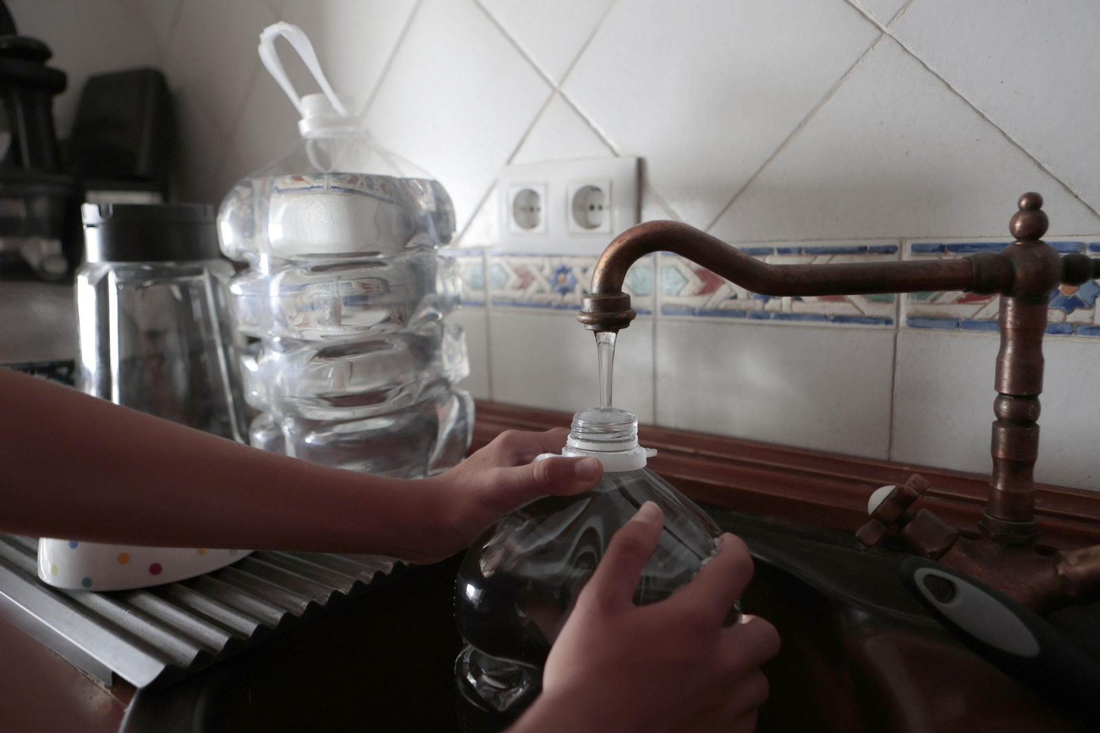 Un vecino de la Sierra rellena botellas de agua ante las restricción