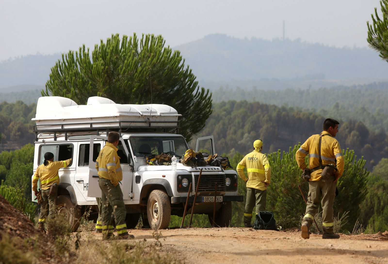 Un grupo de bomberos forestales observa el monte, después de haber finalizado su intervención nocturna para aplacar las llamas.