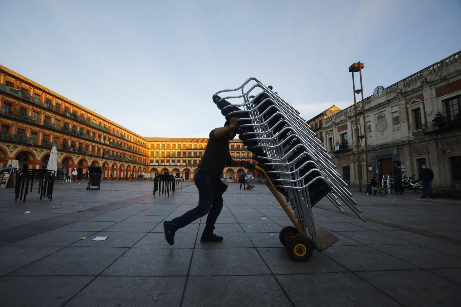 Un trabajador recoge las terrazas en La Corredera.