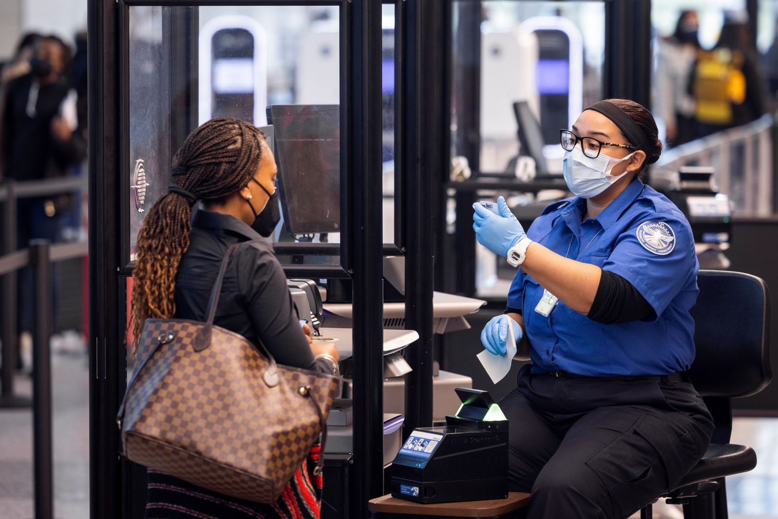 Una trabajadora del aeropuerto Ronald Reagan en Arlington, EEUU, comprueba el pasaporte covid de una pasajera