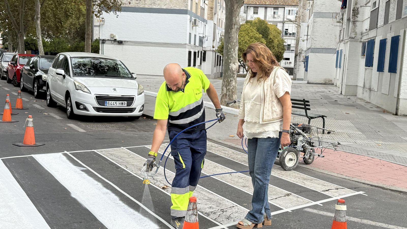 Operario pintando el pao de peatones junto a la concejala Milagros Rodríguez.