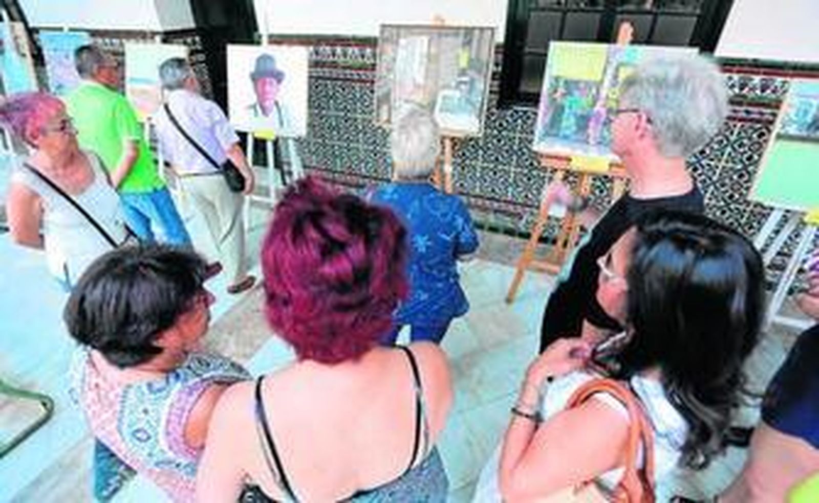 Varios de los asistentes a la exposición, ante la obra 'La hora del café', que ha obtenido el primer premio.