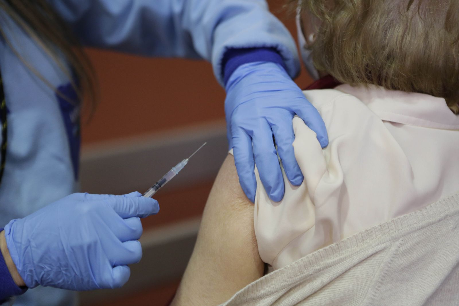 Un profesional sanitario vacuna contra el covid a una persona.