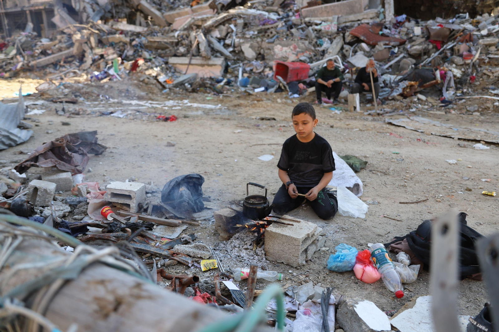 Un niño cocina entre escombros en la ciudad de Gaza.