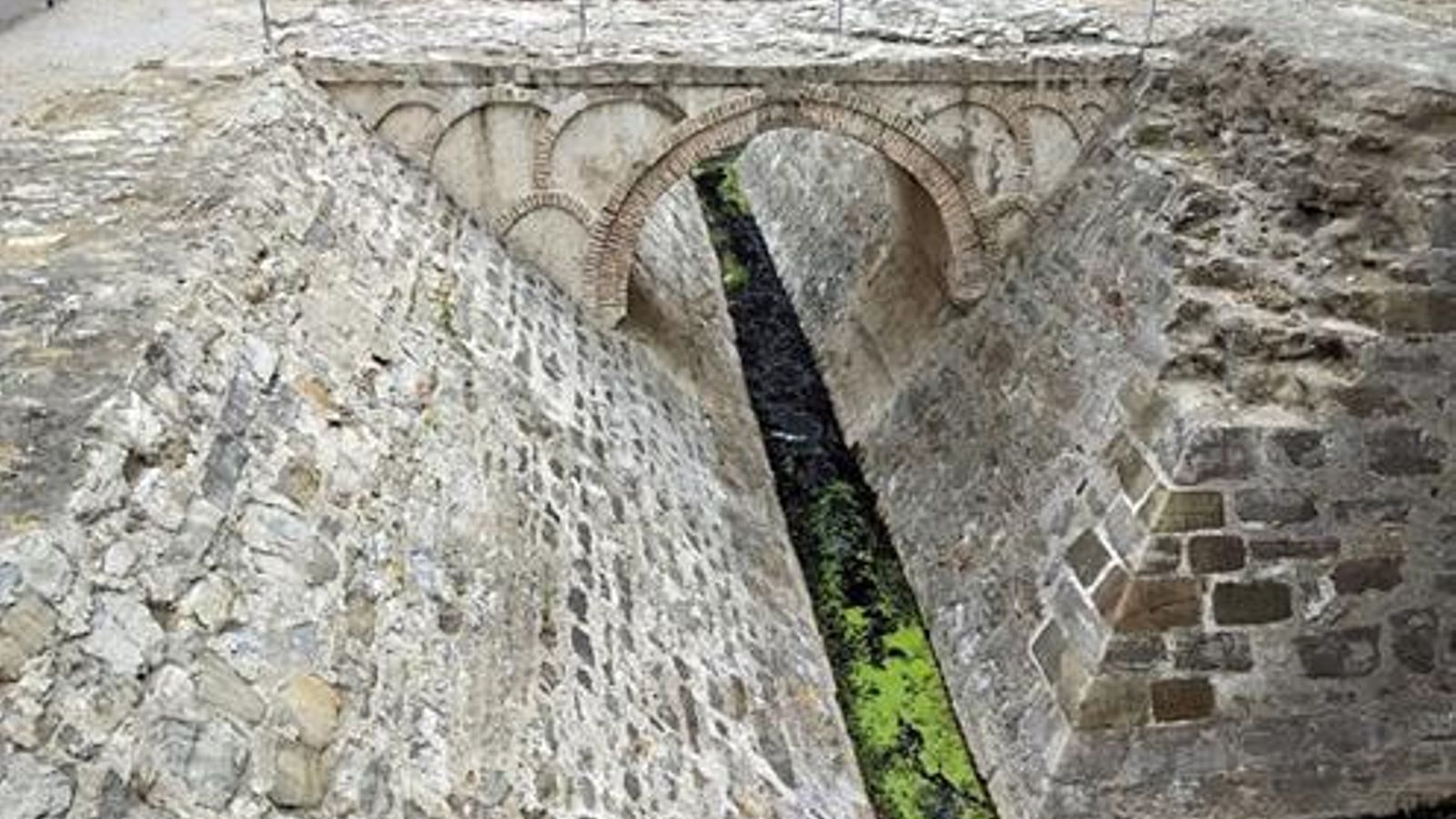 Un codo del foso, de perfecta y documentada obra cristiana de cantería, con el puente mudéjar