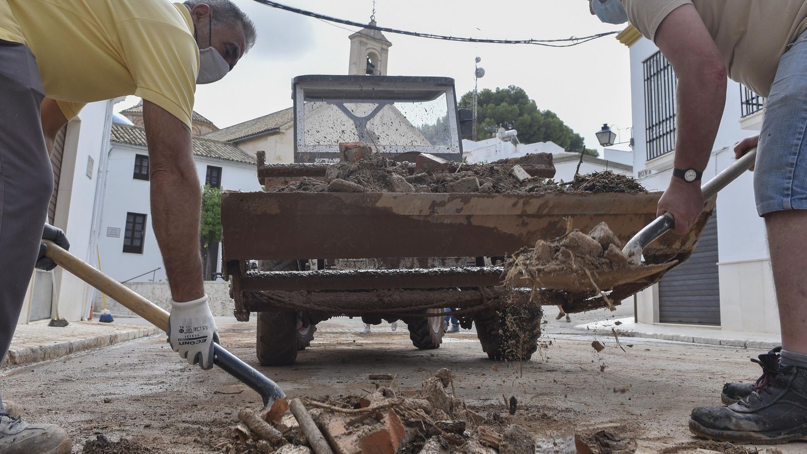 Dos operarios retiran escombros de una calle de Estepa.