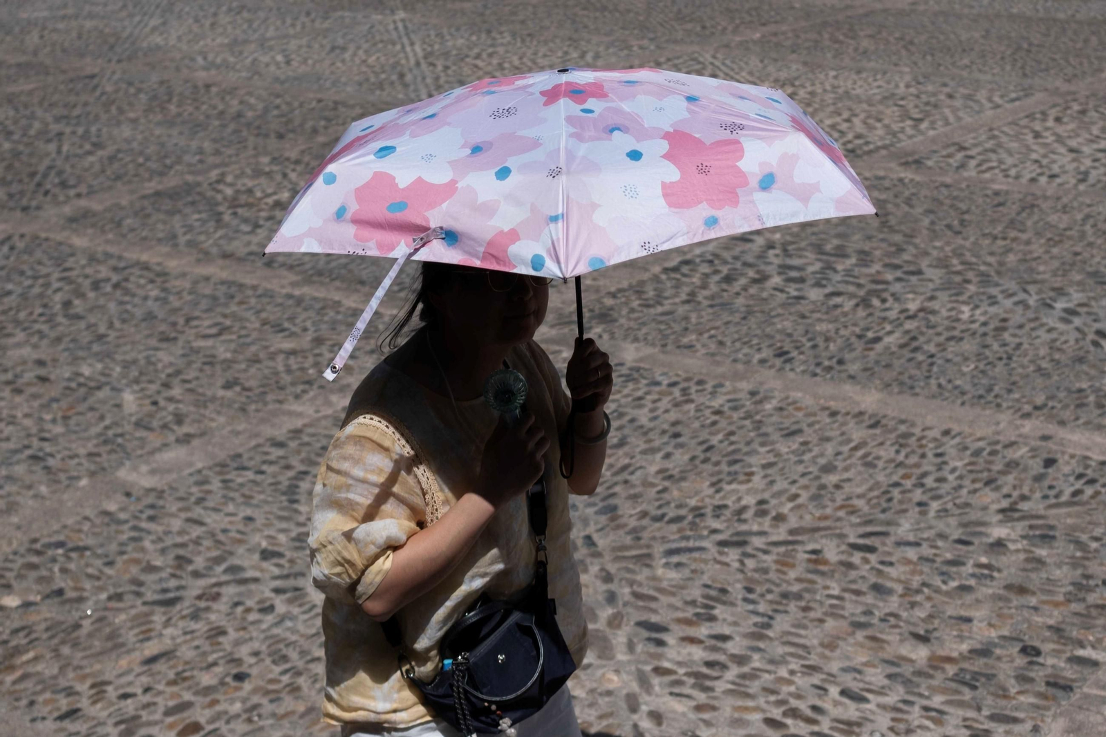 Una turista en Ronda, con sombrilla para protegerse del sol, y un ventilador de mano.
