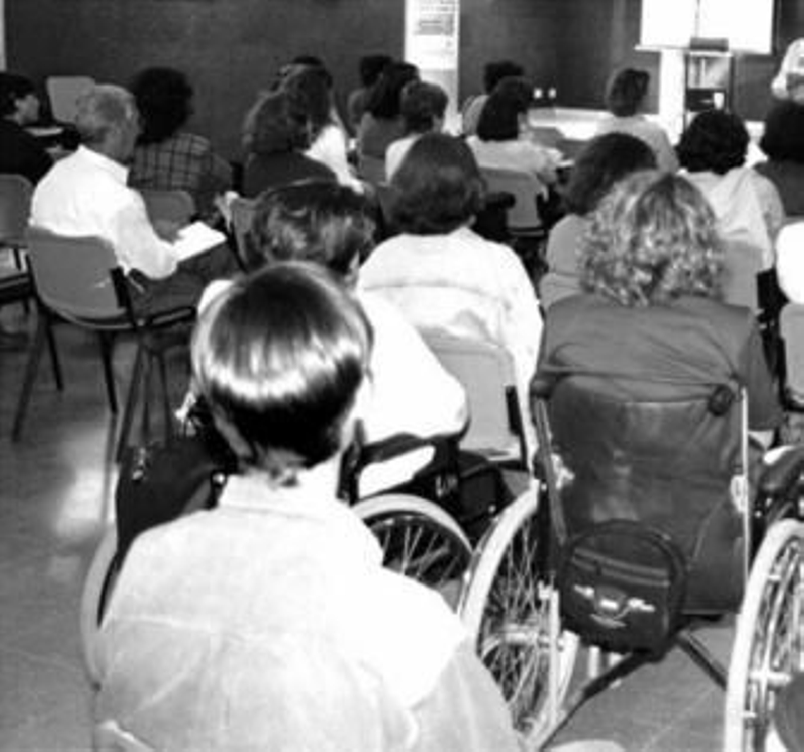 Varias mujeres en silla de ruedas asisten a una charla.