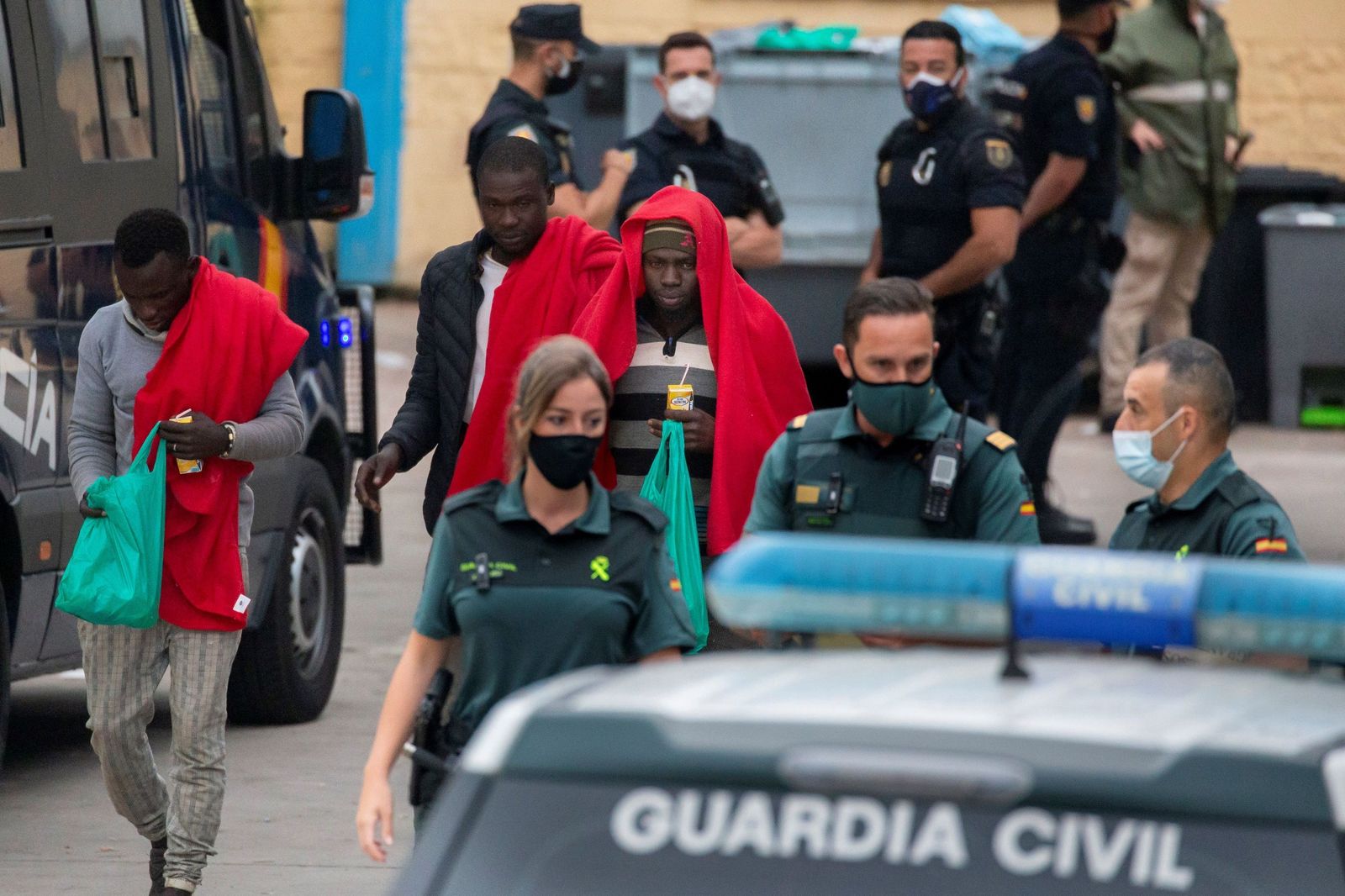 Varios inmigrantes son acompañados por efectivos de la Guardia Civil en un polígono industrial de Ceuta este jueves.