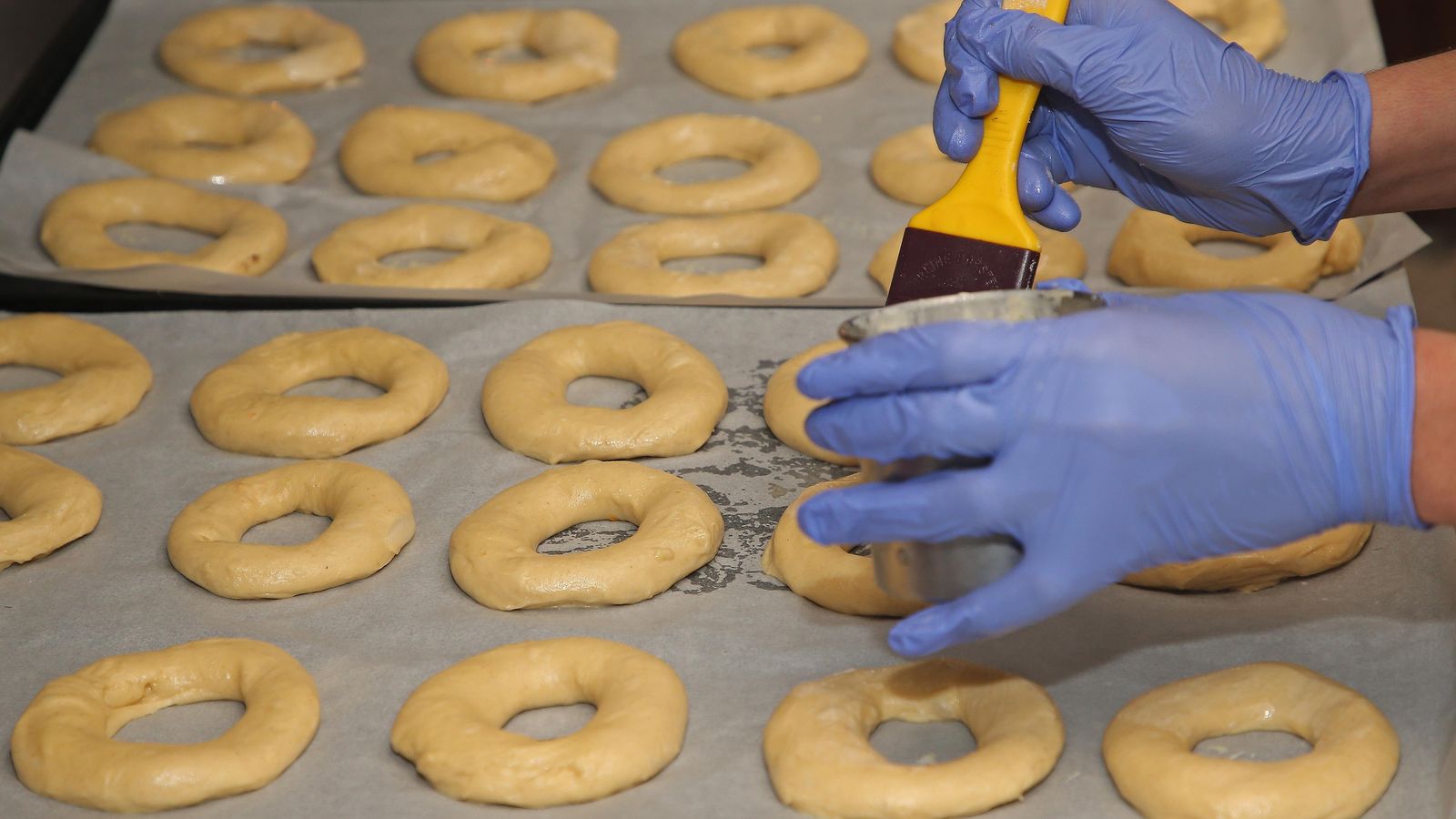 Los pasteleros pintan una tanda de roscones antes de meterlos en el horno.