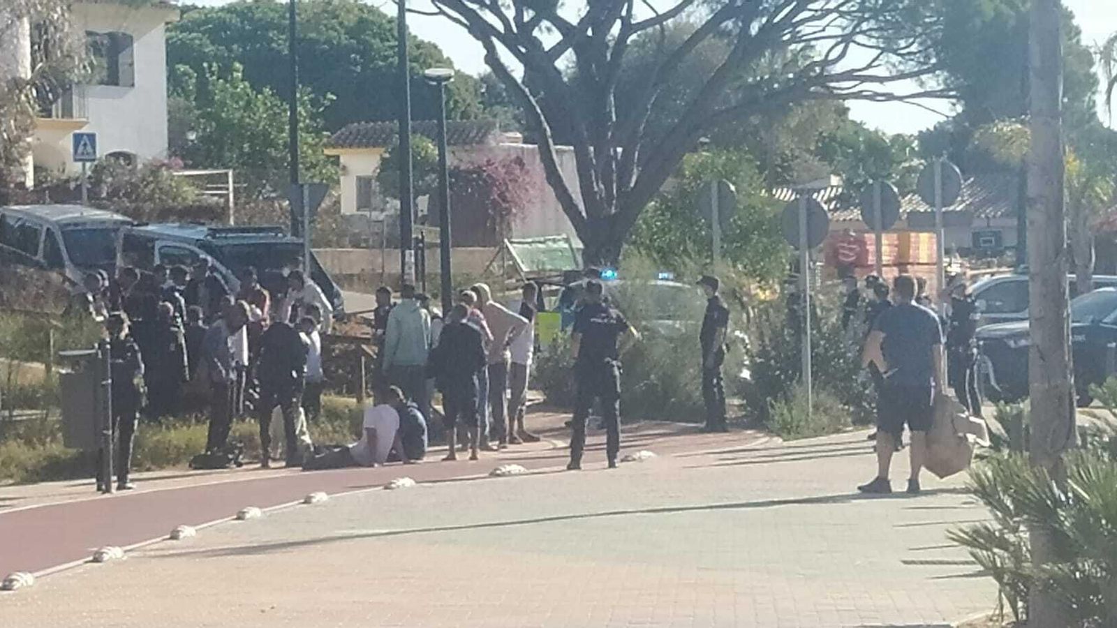 Los inmigrantes, y la Policía, en la zona de aparcamientos de la playa.